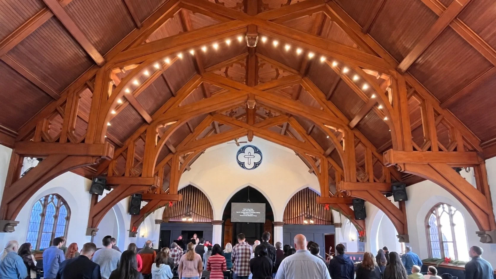 Congregation gathered in the sanctuary at Steel Valley Church, viewed from the rear beneath the timber ceiling