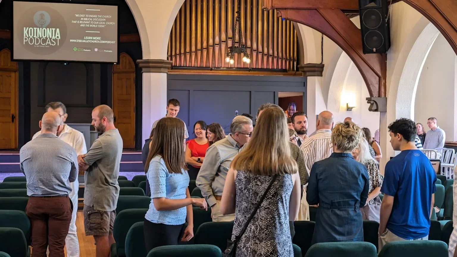 Church members talking together inside the sanctuary after a Sunday gathering
