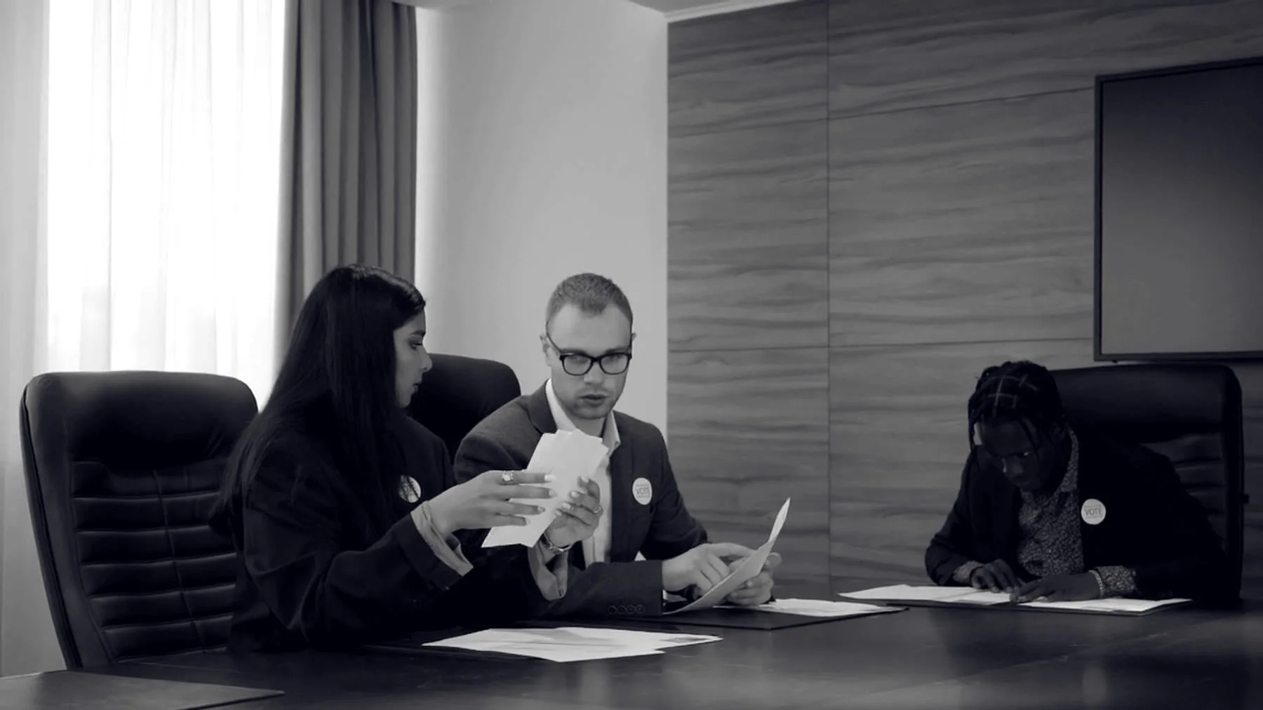 Tres personas revisan documentos en una mesa de reuniones