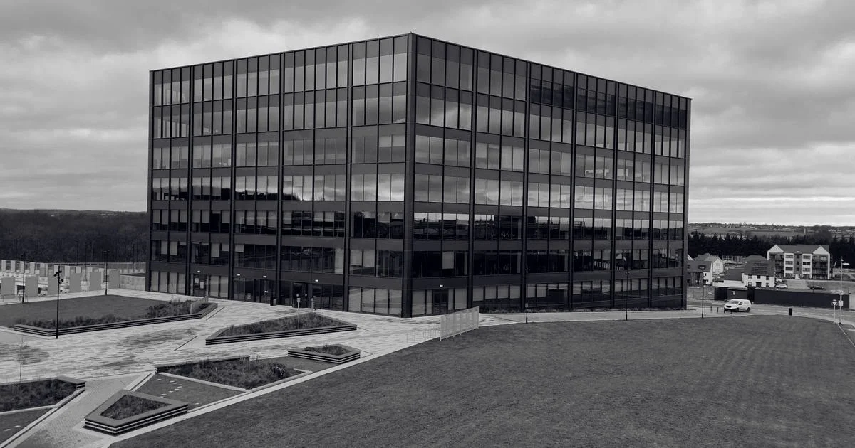 Edificio corporativo de cristal en un paisaje abierto