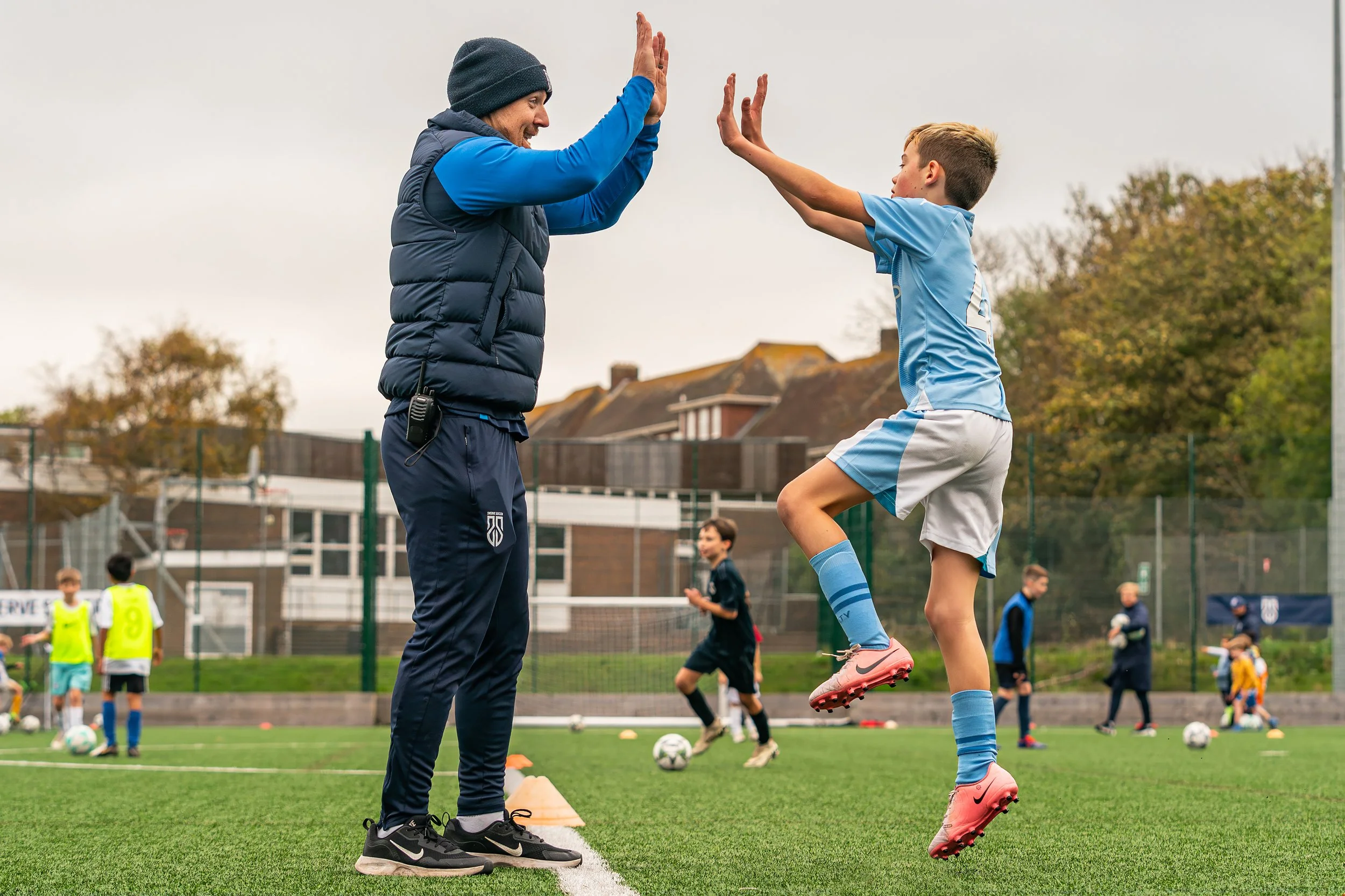 Swerve Soccer coach and player sharing a high-five during football camp