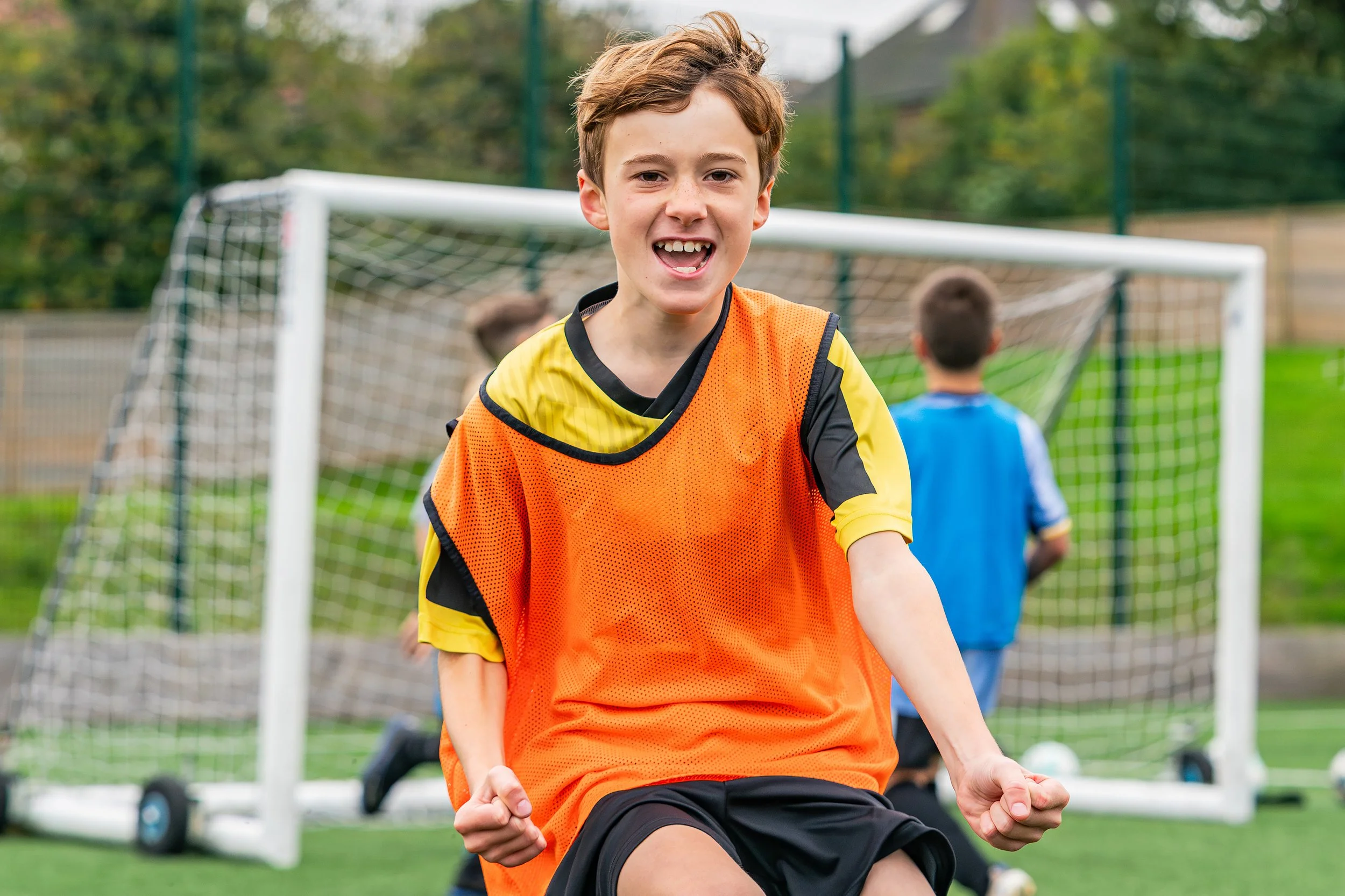 Young footballer in an orange bib enjoying a Swerve Soccer camp in Brighton