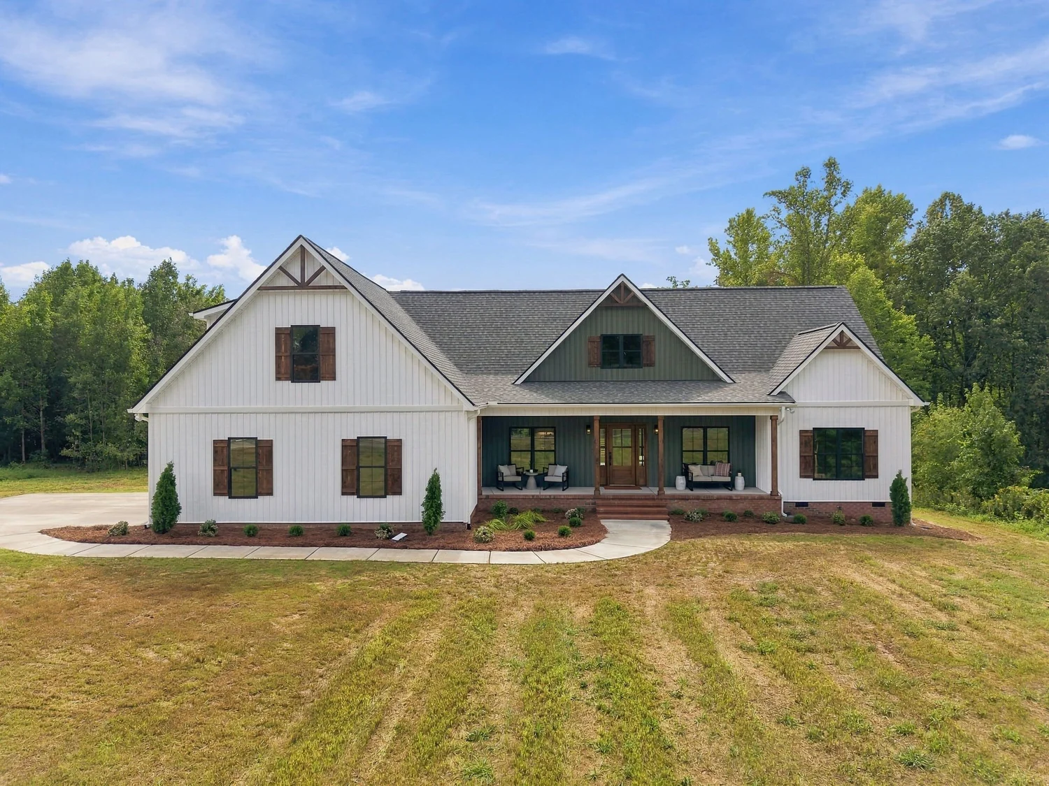 Front of the home: white board-and-batten exterior with a brick base and covered front porch
