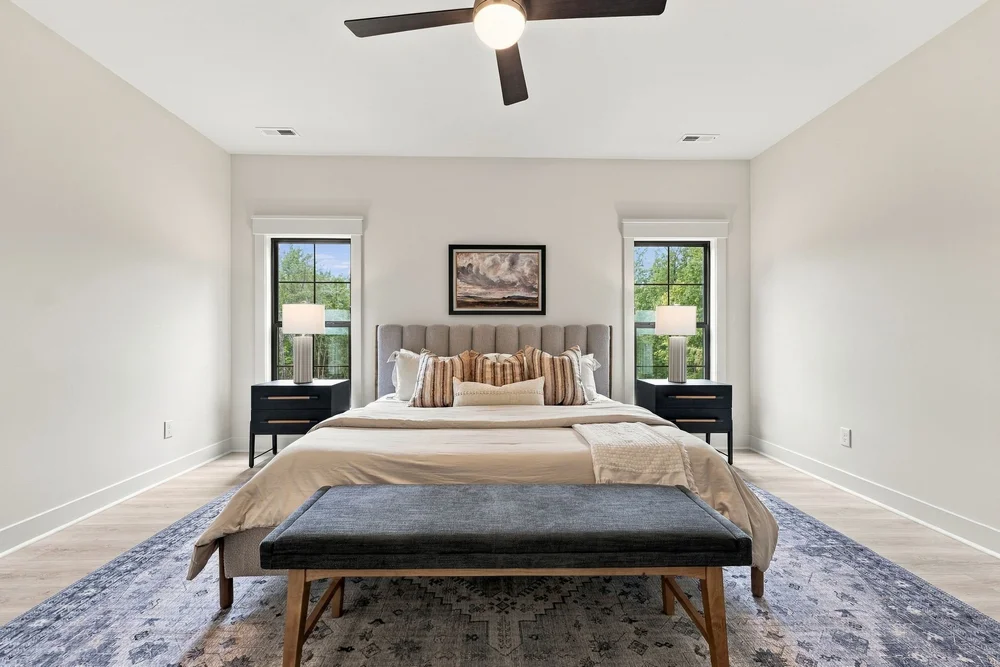 Primary bedroom with a ceiling fan and large windows