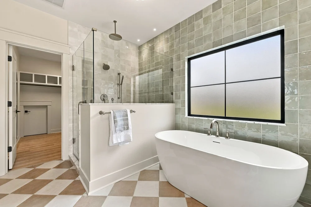 Freestanding soaking tub beside a large window in the primary bath