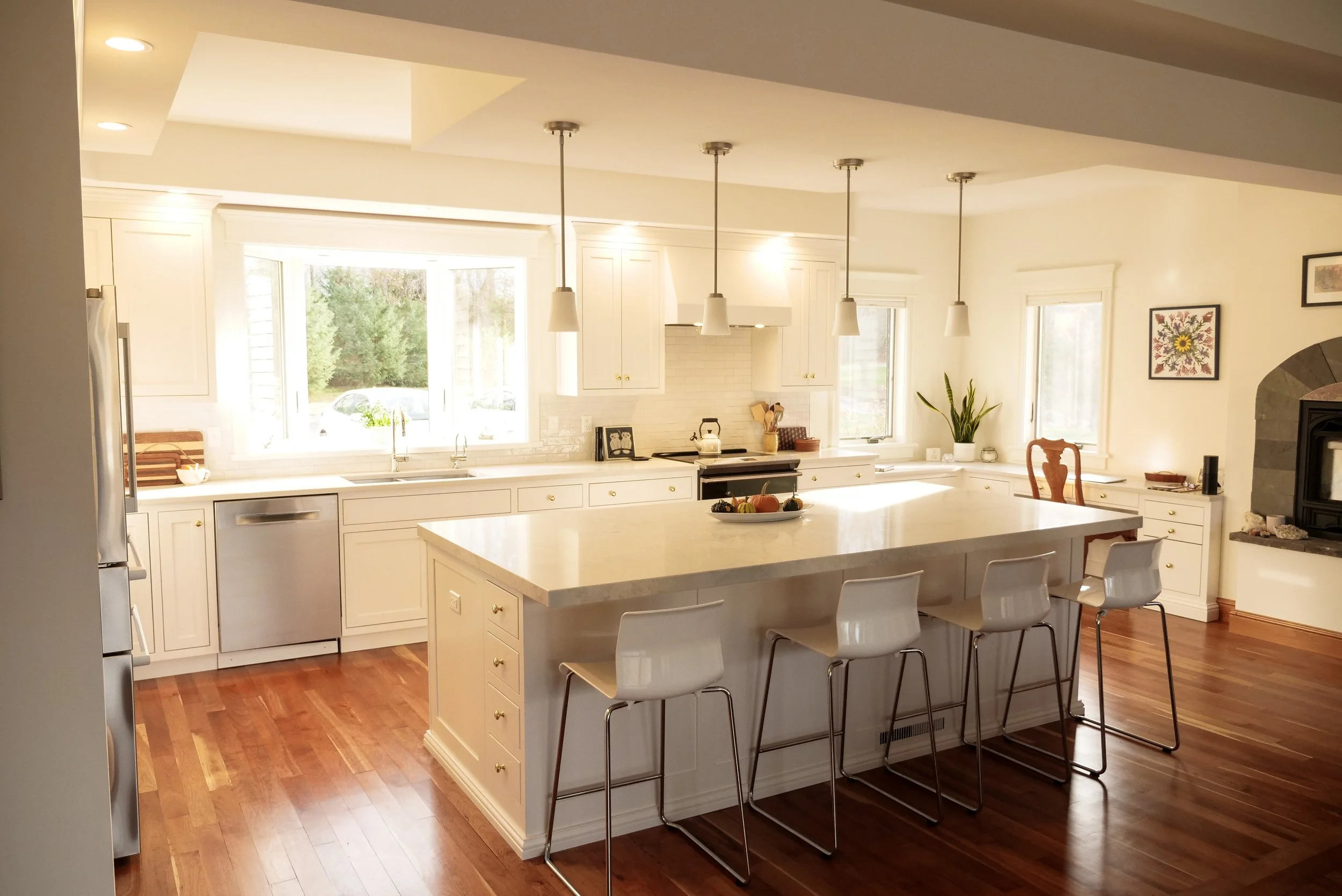 Bright white kitchen with a large island, pendant lights and bar stools, photographed by JD Meyers Productions