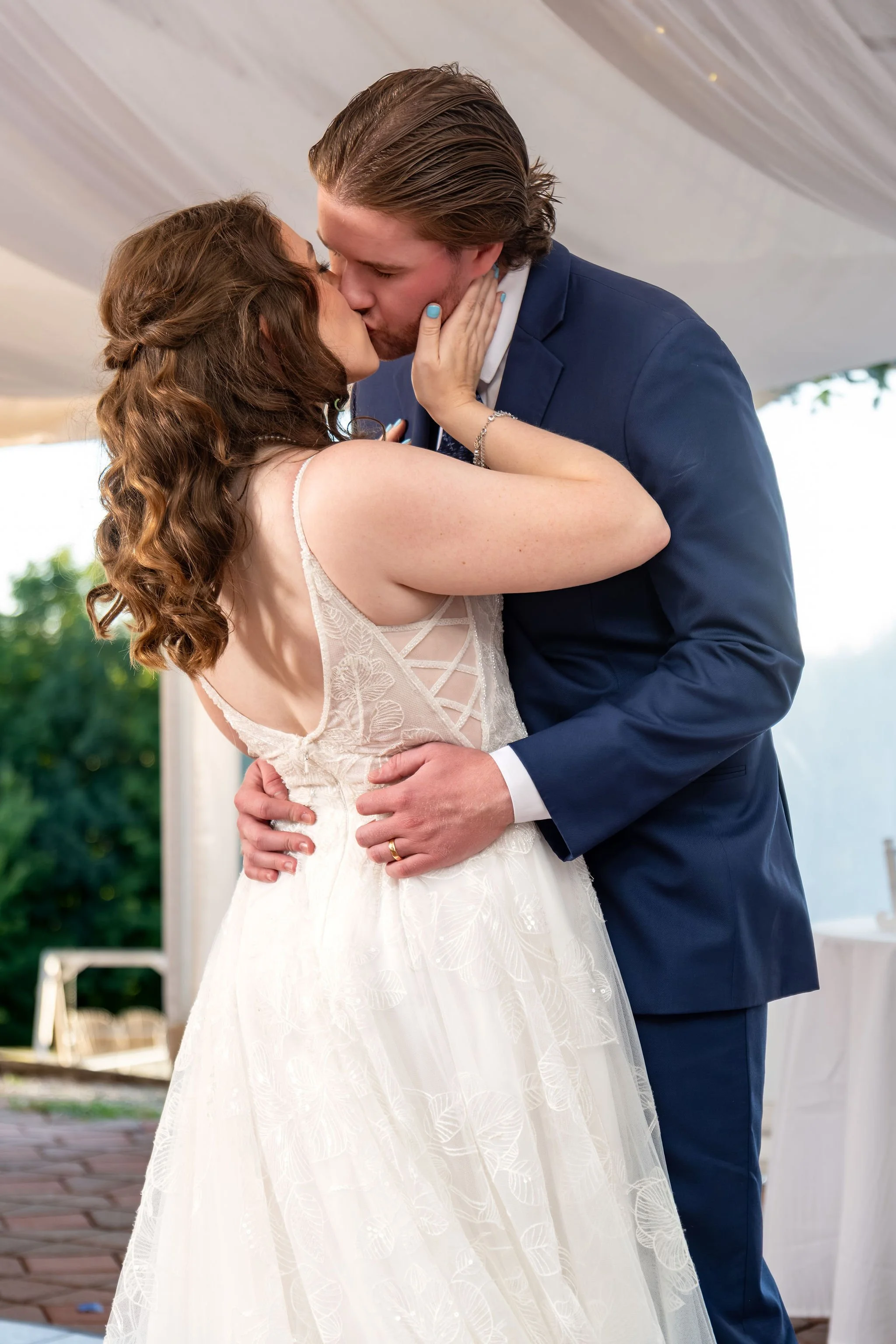 Zachary and Hollie kissing during their first dance under the tent at The Lucerne Inn in Dedham Maine summer wedding photography VMG Productions