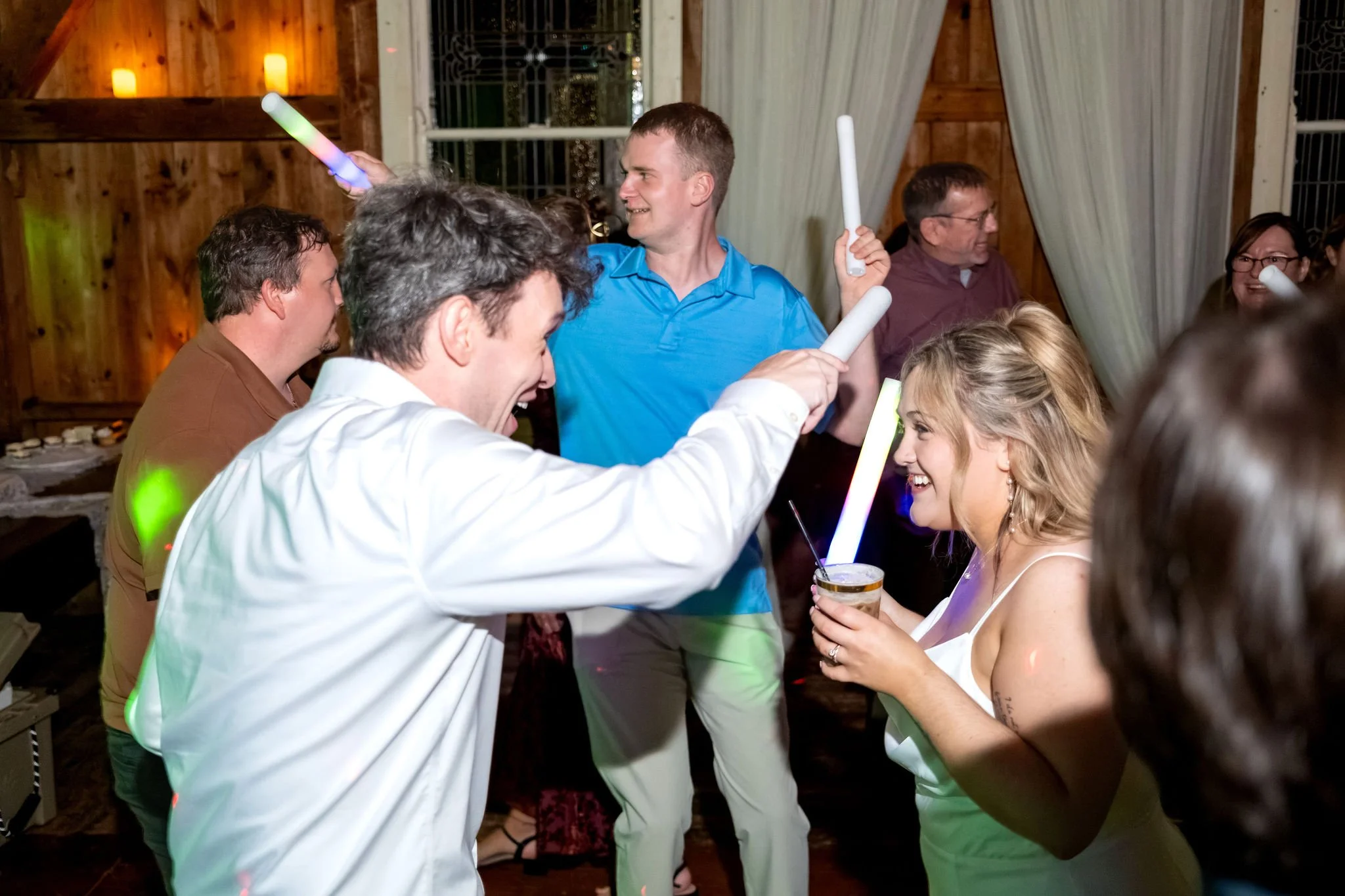Ellie laughing as a groomsman dances up to her with a glow stick at Boothbay Playhouse in Boothbay Maine fall wedding photography VMG Productions
