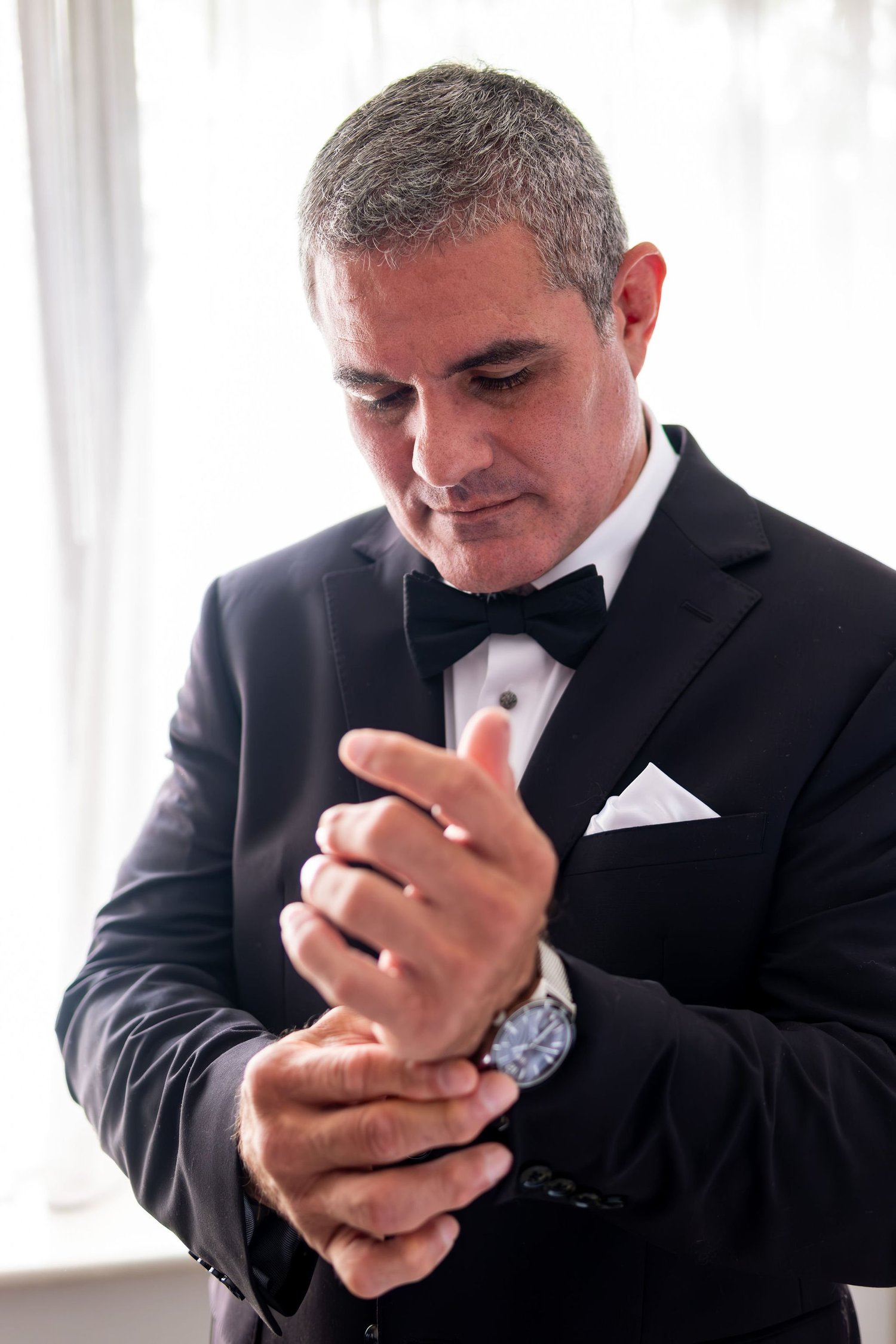 Alexey fastening his watch while getting ready at Portland Sheraton at Sable Oaks South Portland Maine summer wedding photography VMG Productions