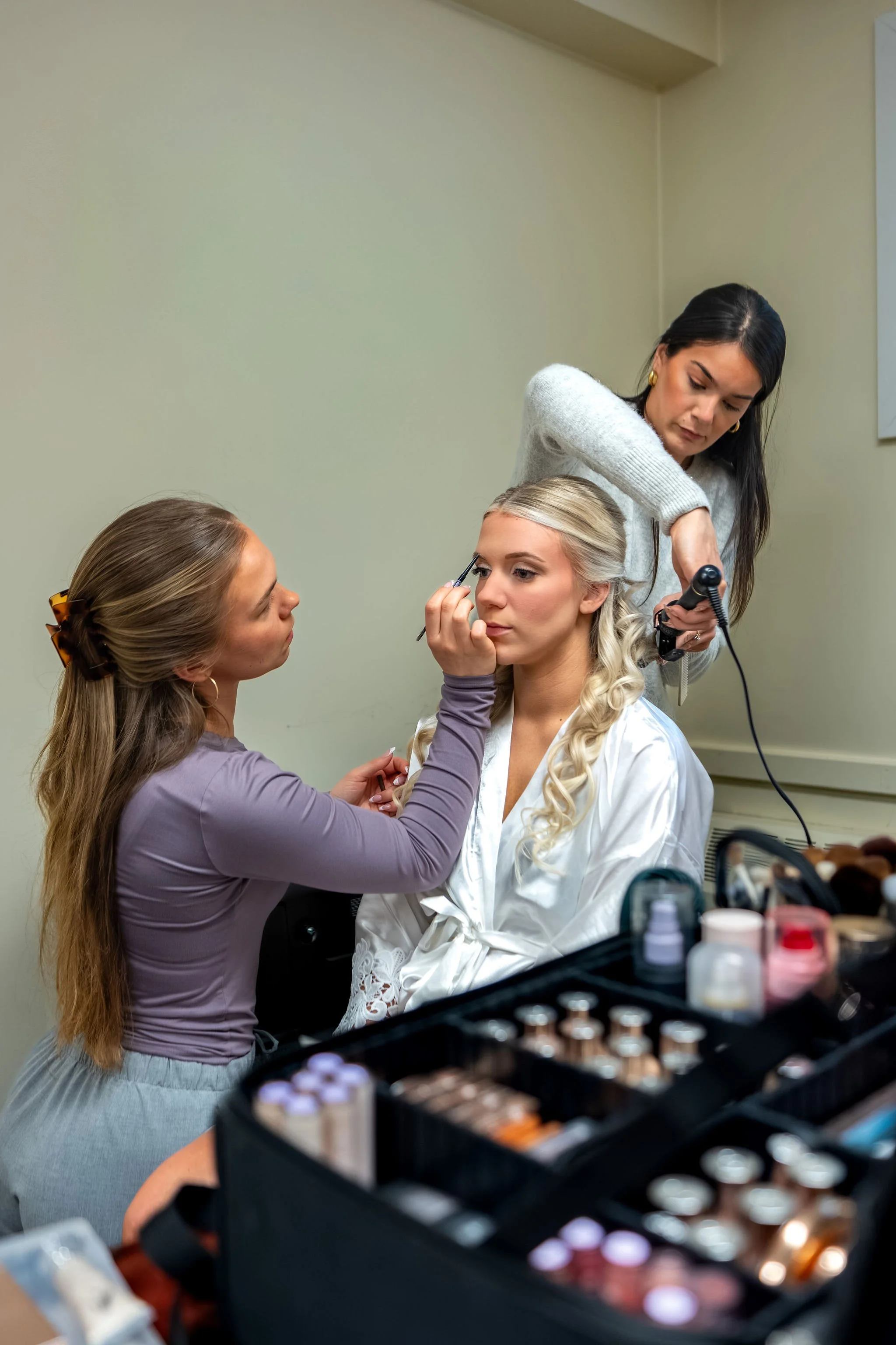 Jeremiah and Vienna wider preparation scene showing bride with both beauty professionals at Holy Trinity Greek Orthodox Church Portland Maine spring wedding photography VMG Productions