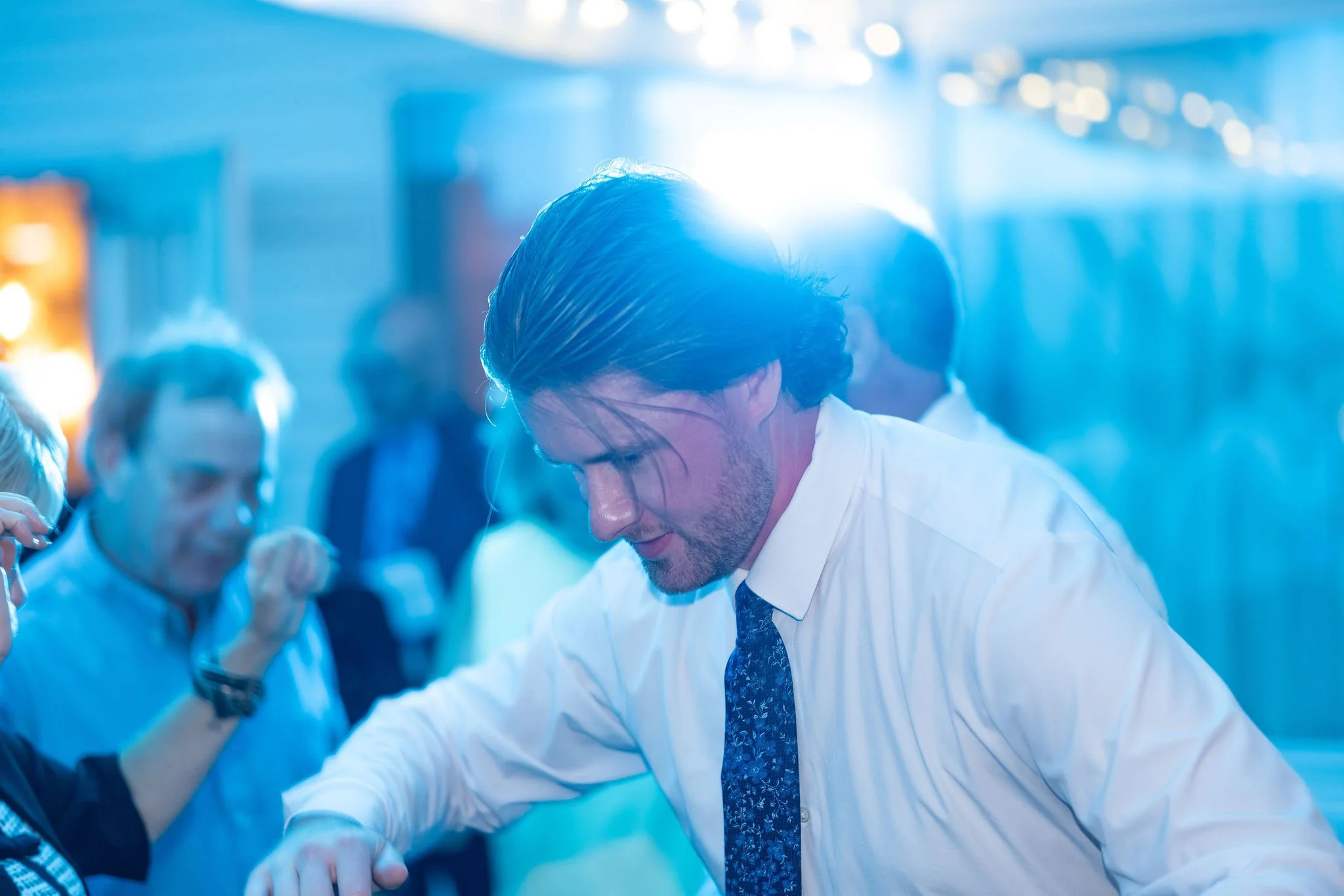 Zachary in his shirt sleeves and floral tie on the dance floor under blue light at The Lucerne Inn in Dedham Maine summer wedding photography VMG Productions