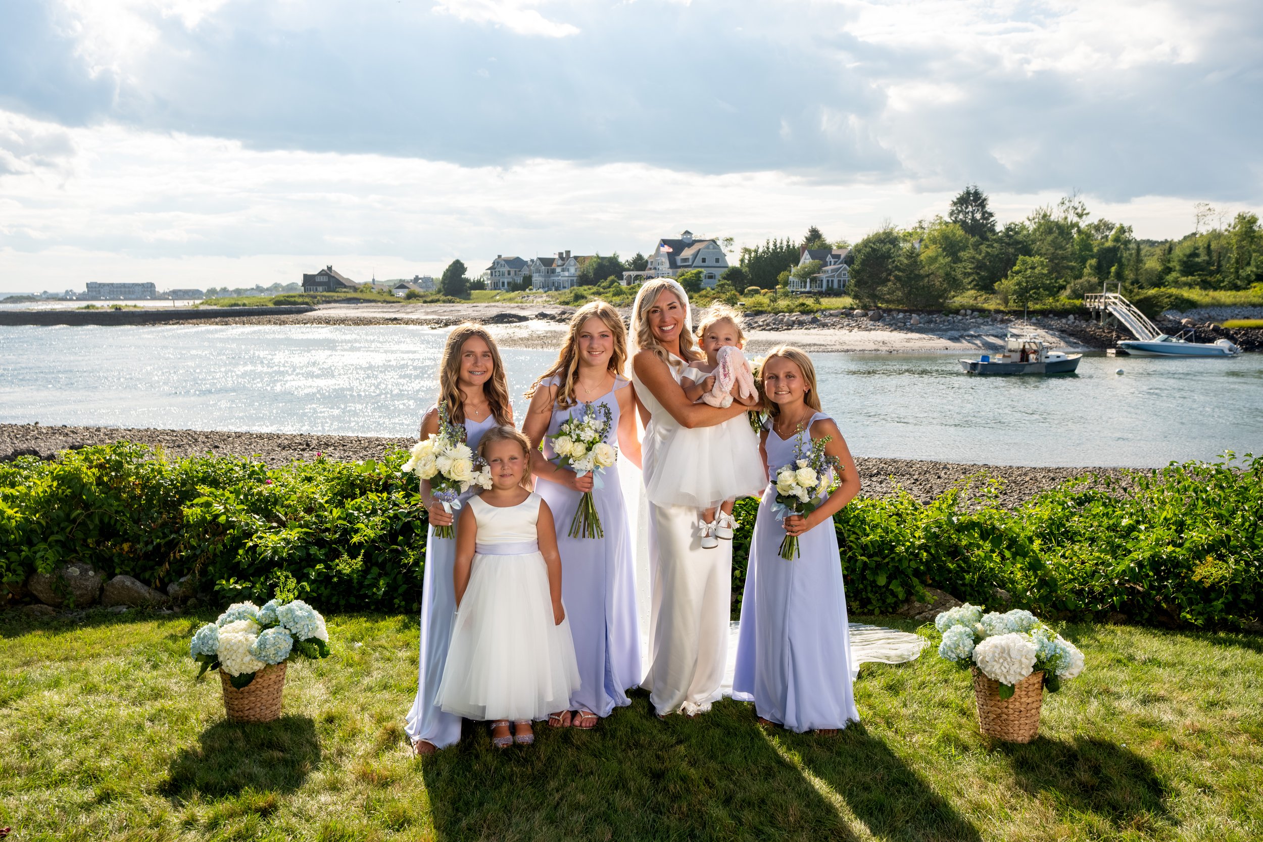 Ashley Draper with her junior bridesmaids and flower girls in light purple by the water at The Breakwater Inn in Kennebunkport Maine summer wedding photography VMG Productions