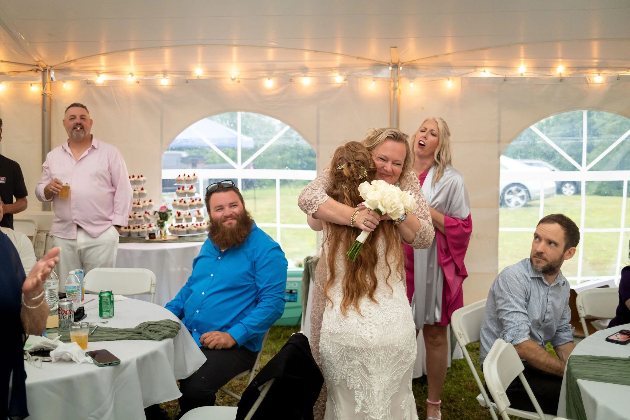Kayla DeAngelis embracing a guest inside the reception tent with the cupcake tower visible behind them at their Sanbornton New Hampshire wedding photography VMG Productions