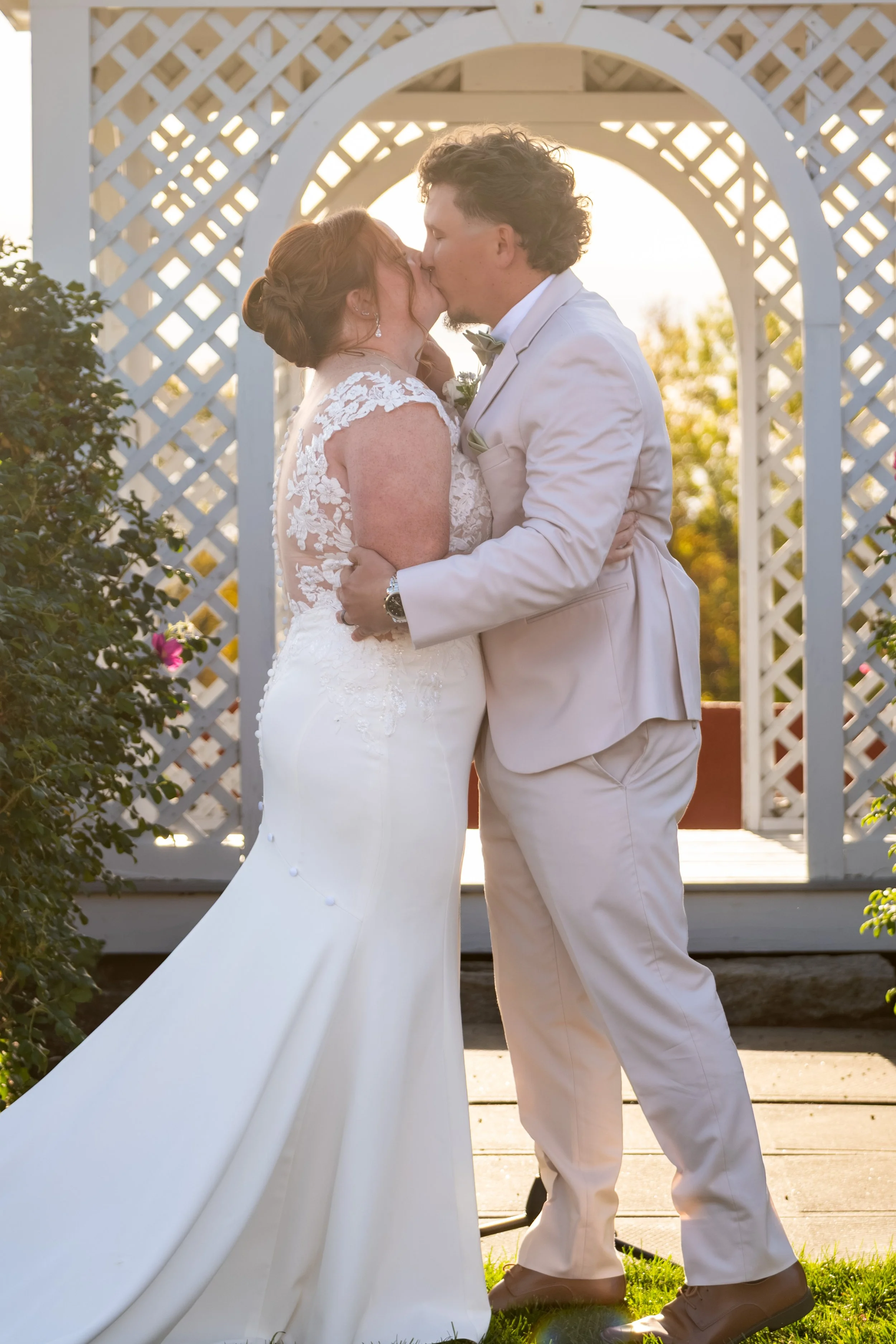 Erika and Andrew sharing their first kiss as a married couple under the lattice gazebo at the Maine Wedding Barn and Event Center in Minot Maine fall wedding photography VMG Productions