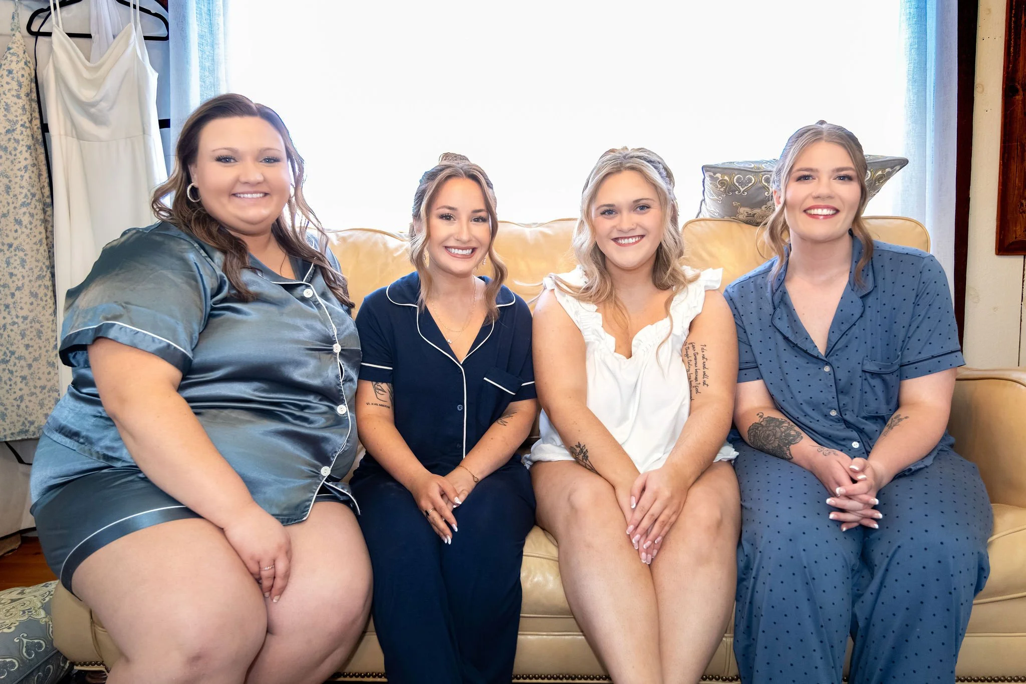 Ellie and her bridesmaids sitting together on a leather couch in pajamas before the ceremony at Boothbay Playhouse in Boothbay Maine fall wedding photography VMG Productions