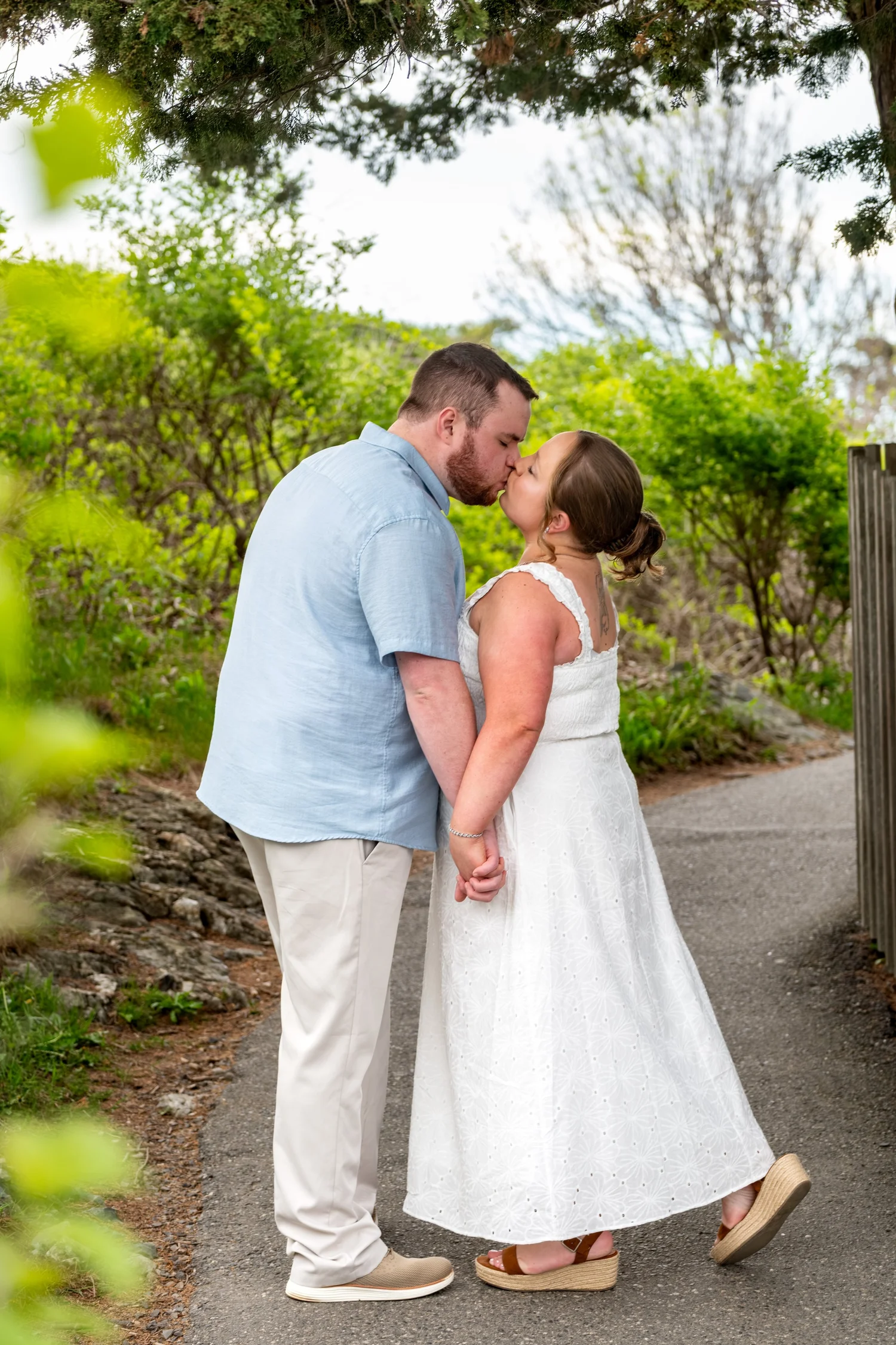 Couple sharing a kiss on a garden path in Ogunquit, Maine, by VMG Productions