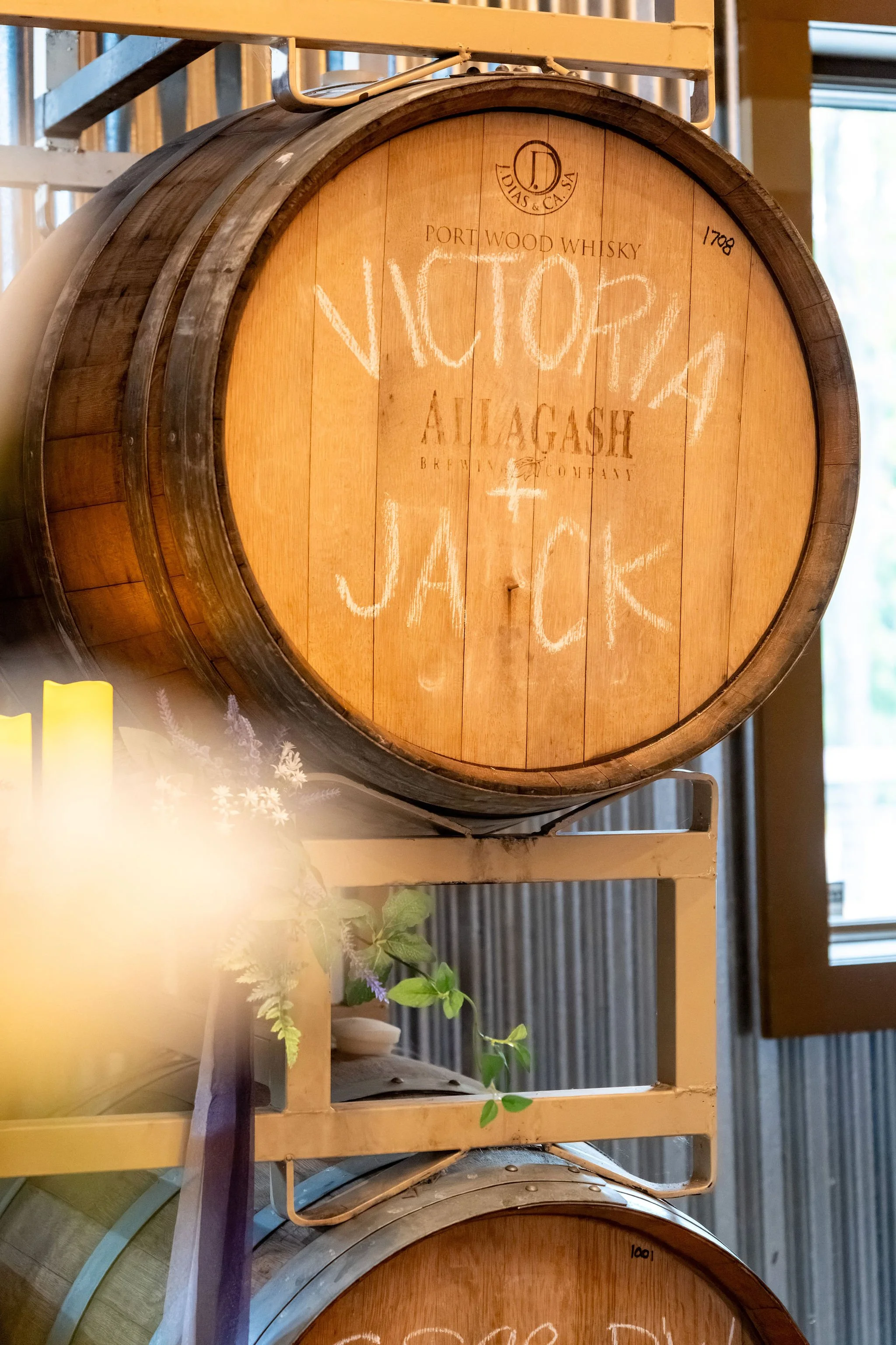 Victoria and Jack's names chalked on an Allagash whiskey barrel in the barrel room at The Cellars at Allagash Brewing Company in Portland Maine fall wedding photography VMG Productions