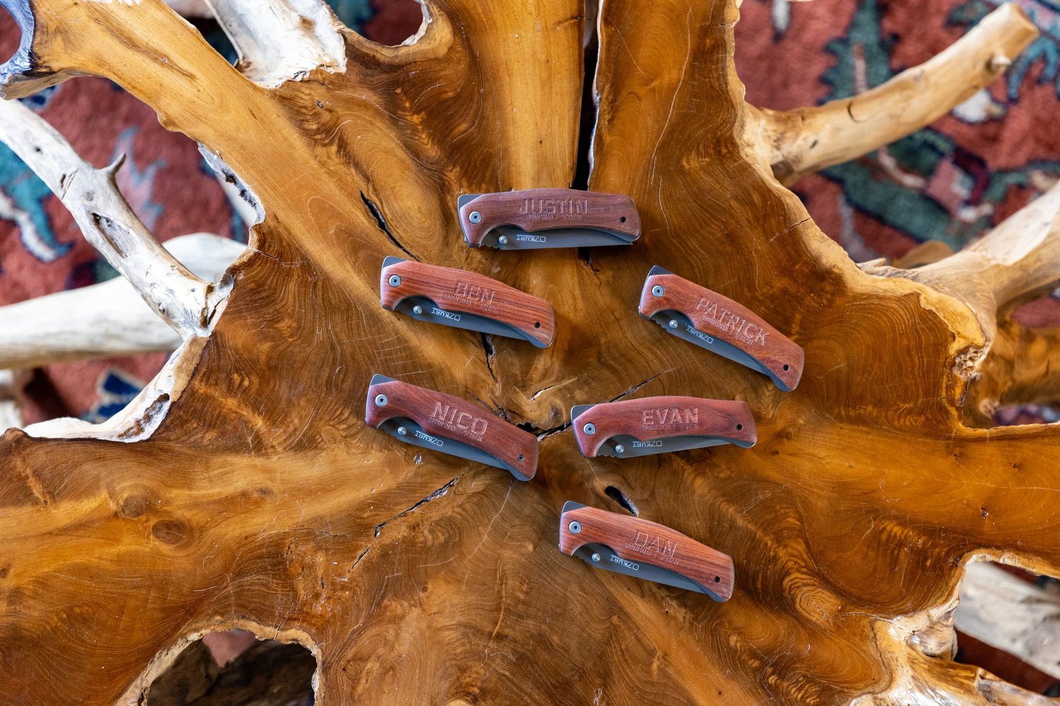 Personalized engraved pocket knives arranged as groomsmen gifts on live edge wood slab at Wentworth Inn Jackson New Hampshire wedding