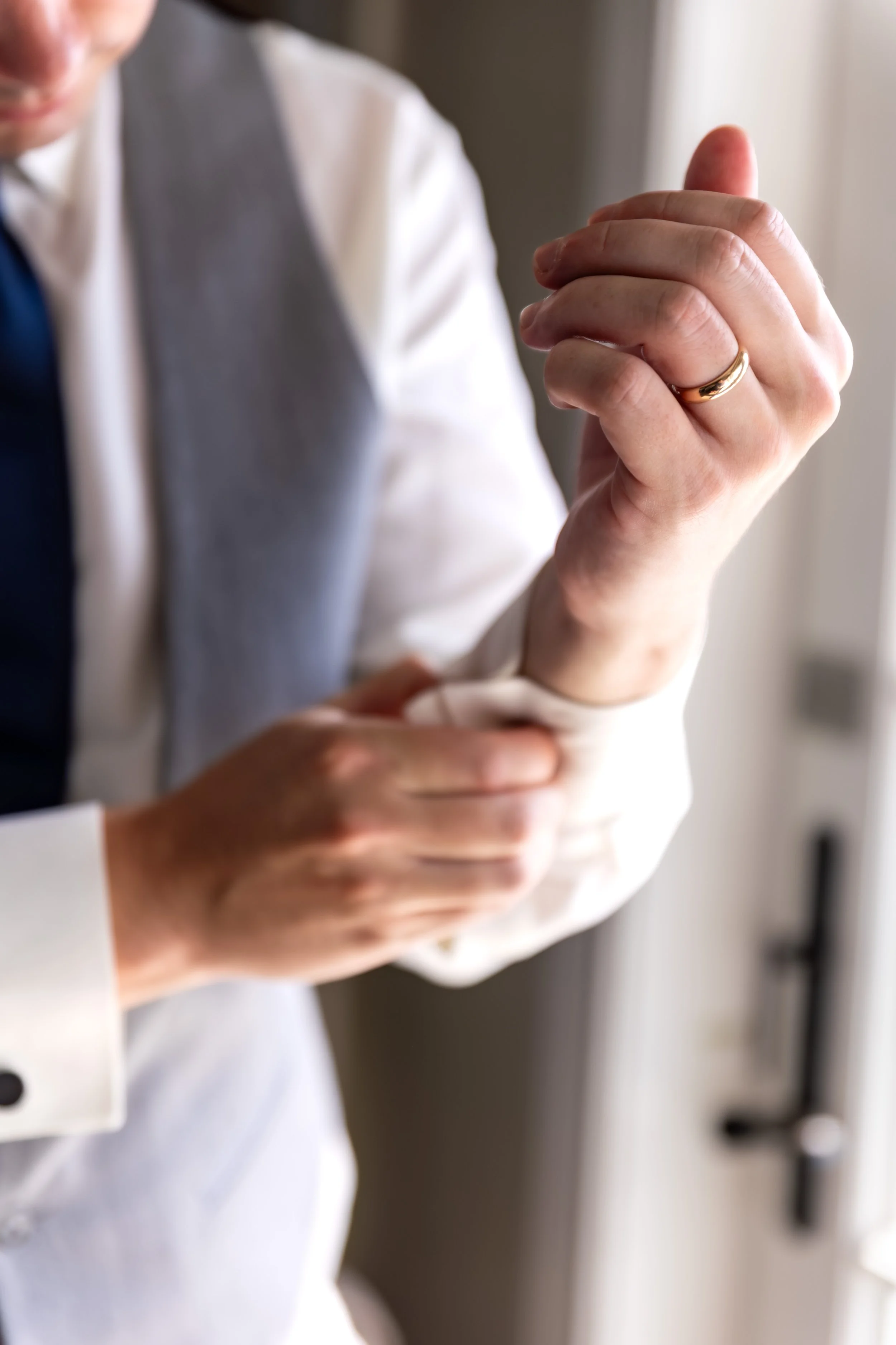 Anthony Pirolli adjusting his cufflinks with his gold wedding band visible while getting ready at Union Bluff Hotel in York Maine wedding photography VMG Productions