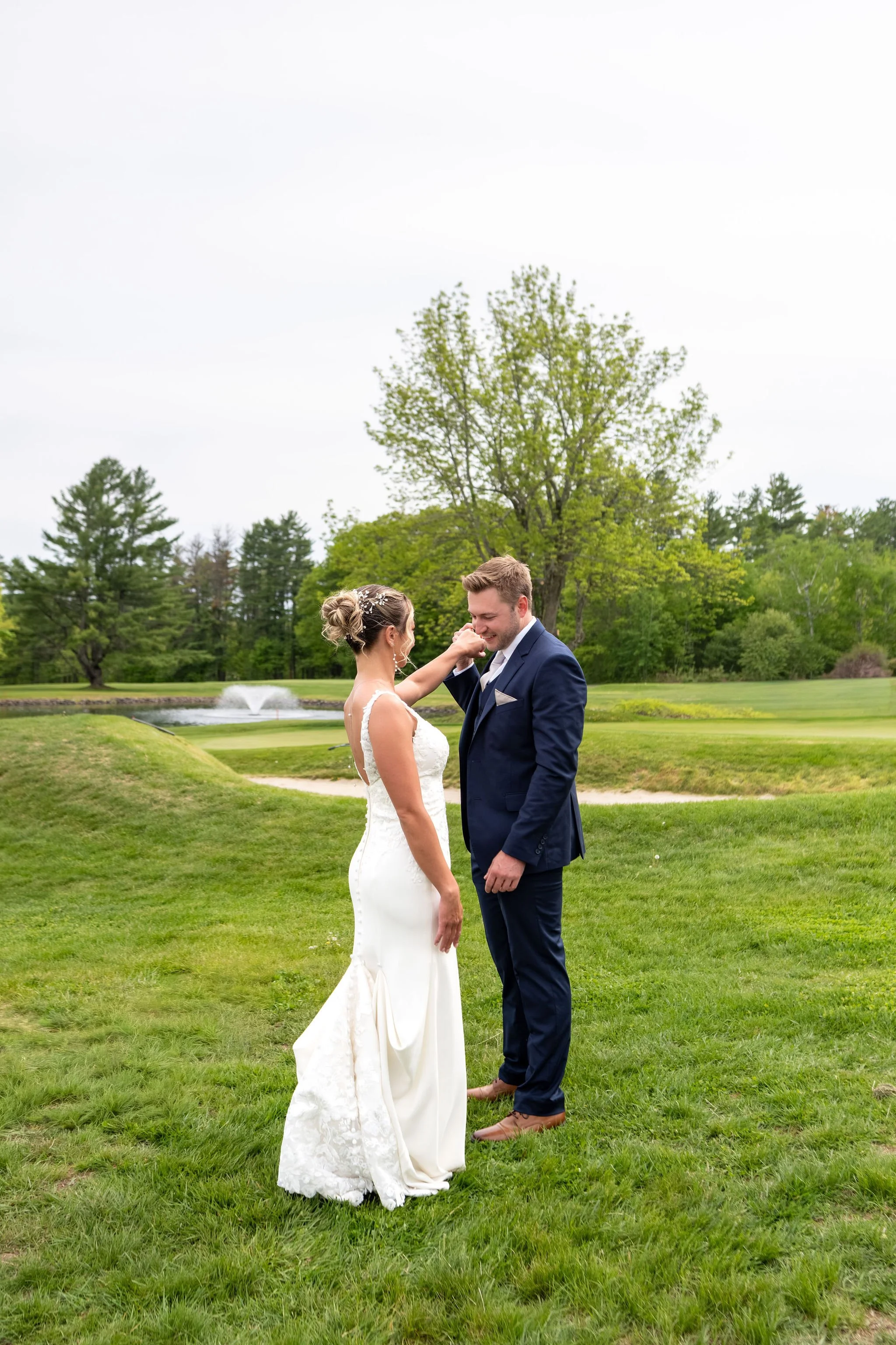 Beth and Cameron groom kissing the bride's hand at their first look at Augusta Country Club Manchester Maine spring wedding photography VMG Productions