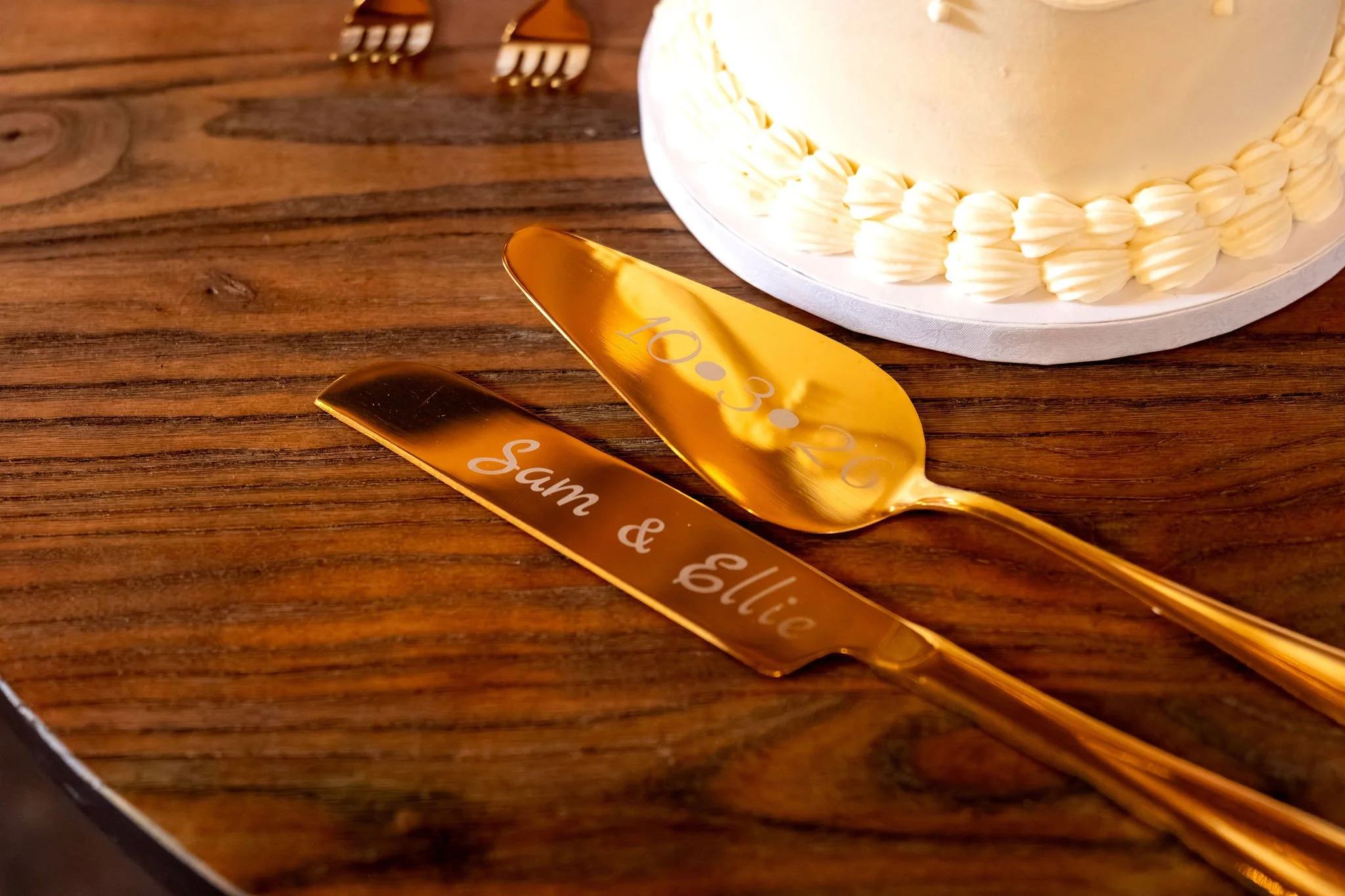 Gold cake server and knife engraved with Sam and Ellie beside the cake at Boothbay Playhouse in Boothbay Maine fall wedding photography VMG Productions