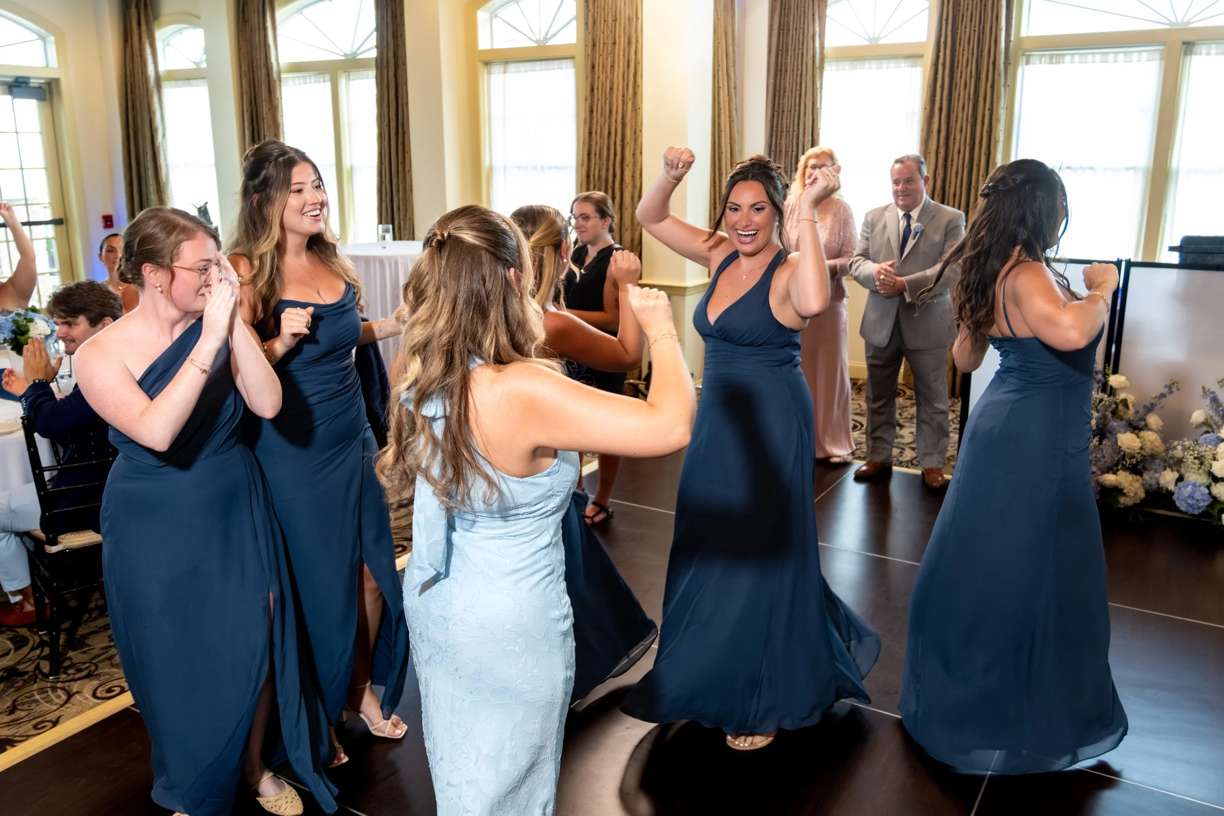 Caroline Pirolli's bridesmaids in navy dancing into the reception during the grand entrance at Union Bluff Hotel in York Maine wedding photography VMG Productions