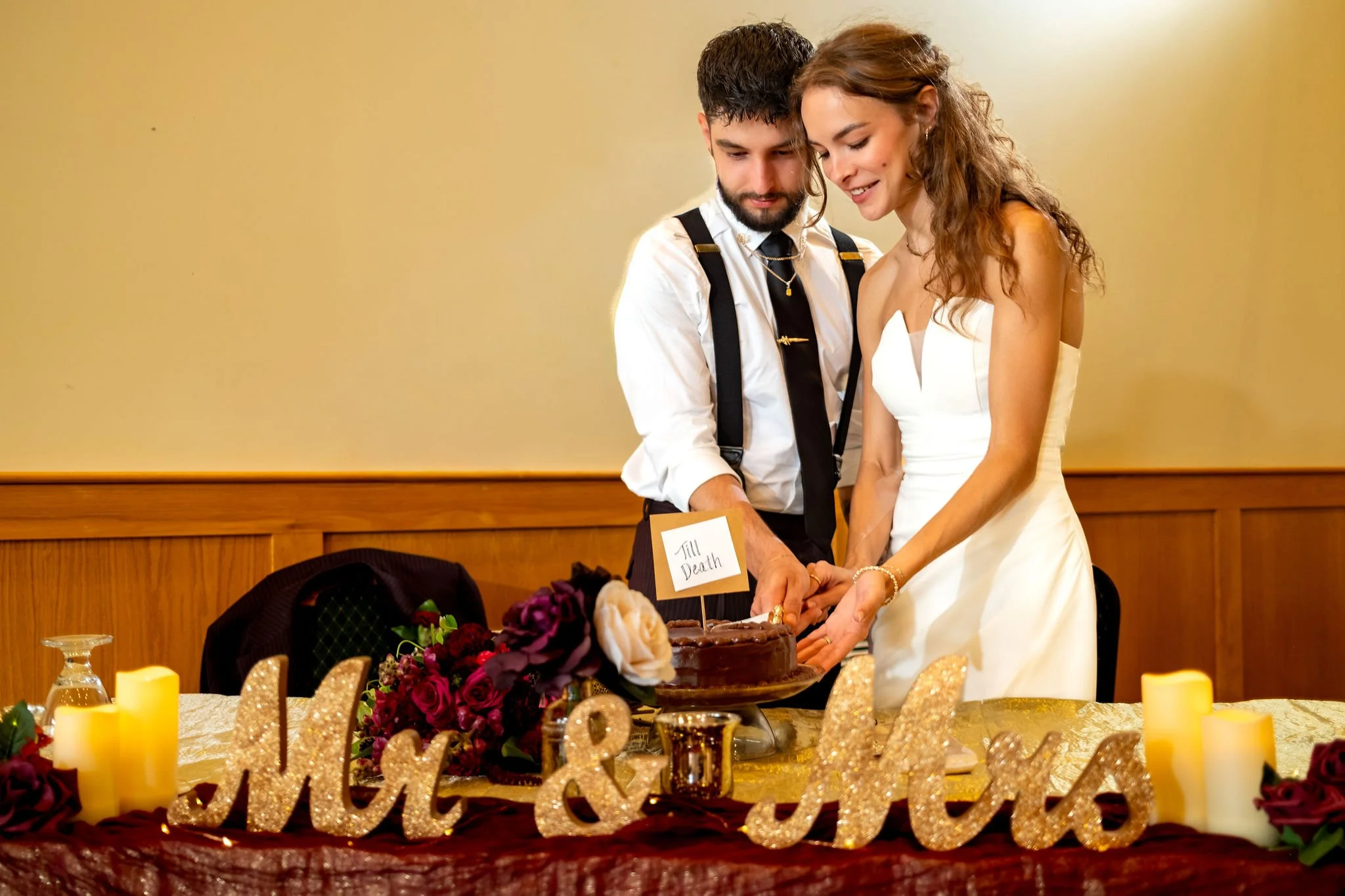 Cassidy and Chase Begin cutting their cake at the head table at Maple Hill Farm Inn and Conference Center in Hallowell Maine summer wedding photography VMG Productions