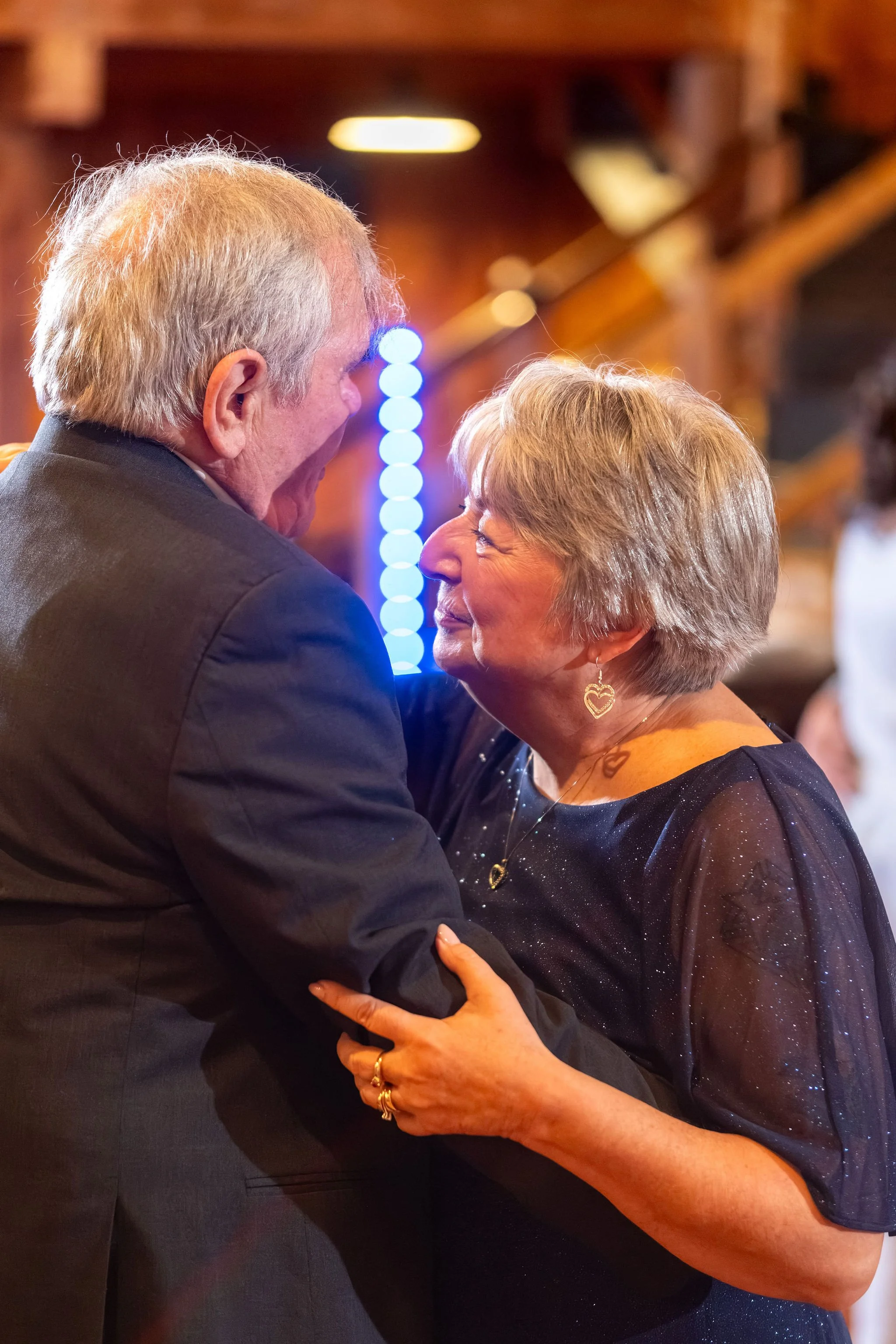 An older couple dancing close and sharing a smile at Boothbay Playhouse in Boothbay Maine fall wedding photography VMG Productions