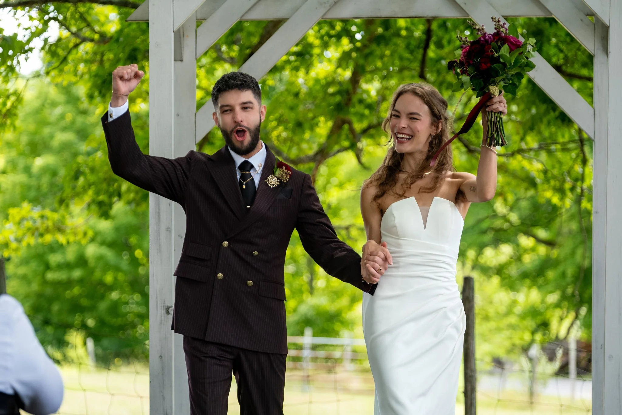Chase Begin raising both fists as he and Cassidy are pronounced married at Maple Hill Farm Inn and Conference Center in Hallowell Maine summer wedding photography VMG Productions
