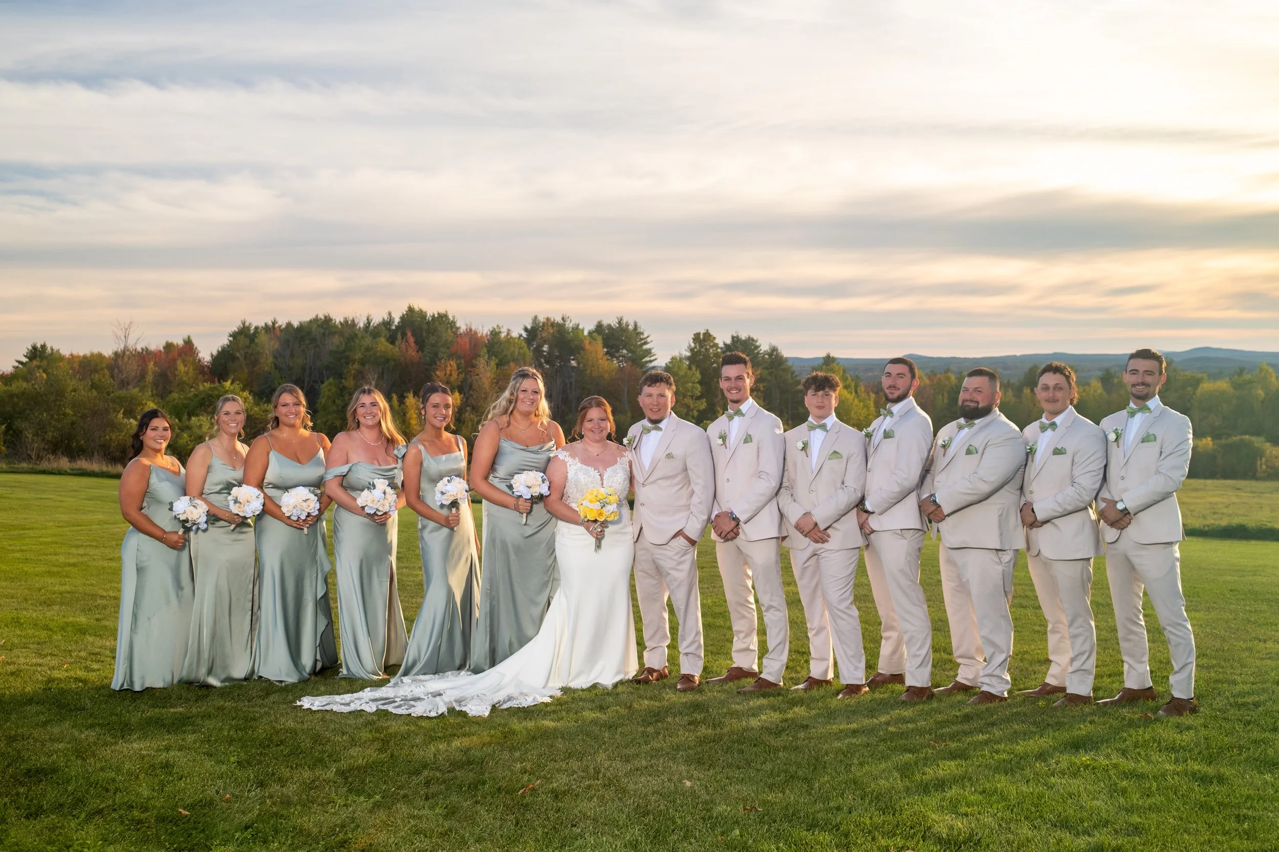 Erika and Andrew with the whole wedding party lined up on the lawn at golden hour at the Maine Wedding Barn and Event Center in Minot Maine fall wedding photography VMG Productions