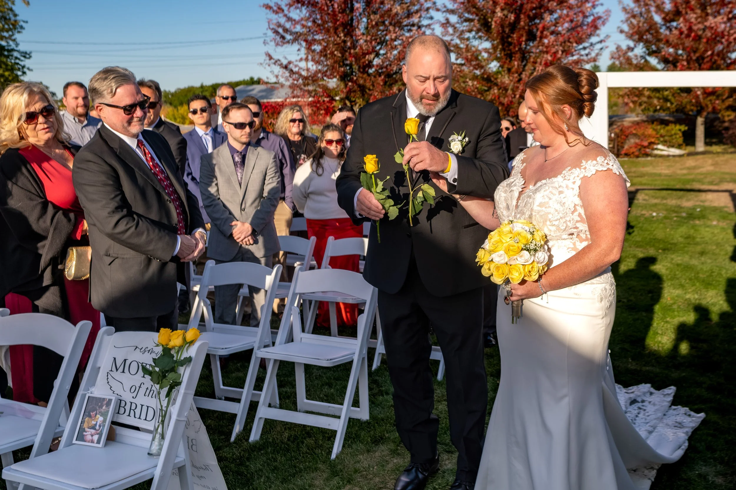 Erika walking down the aisle on her dad's arm holding a yellow rose and her bouquet at the Maine Wedding Barn and Event Center in Minot Maine fall wedding photography VMG Productions