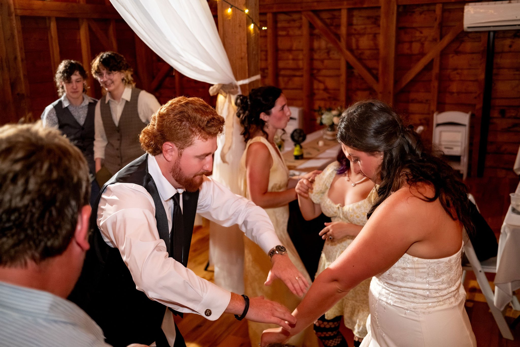 Alyssa and Colby dancing together in the middle of the reception crowd at the 1888 Barn Bethel Maine summer wedding photography VMG Productions