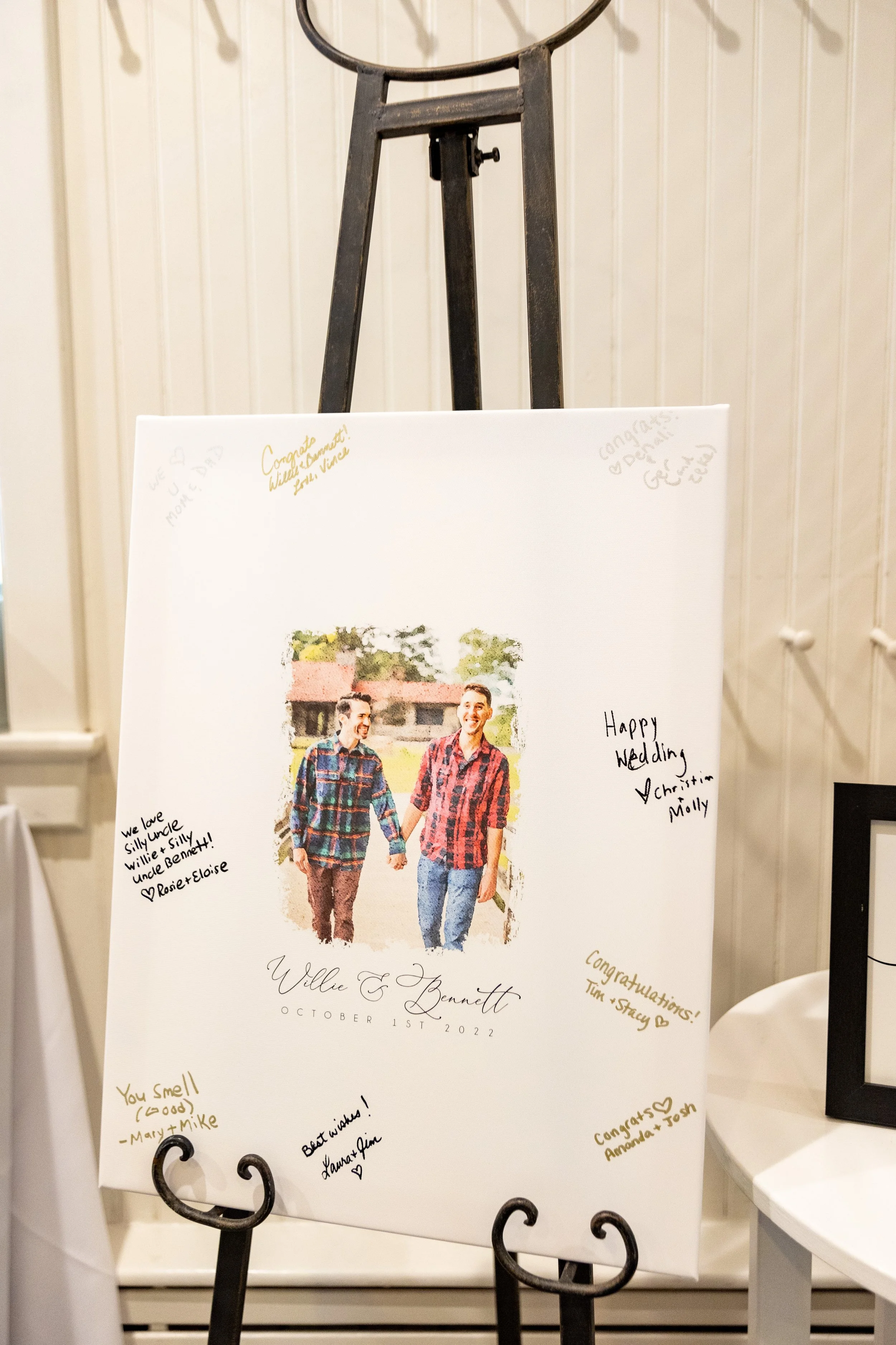 Wedding guest book signature canvas on easel at The Inn on Peaks Island Portland Maine with watercolor effect couple portrait of Bennett and Willie surrounded by handwritten guest messages and signatures October 2022