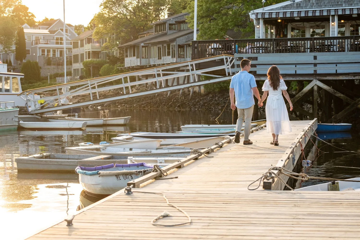 Couple walking the dock past the dinghies at golden hour, Perkins Cove, Ogunquit, Maine, by VMG Productions