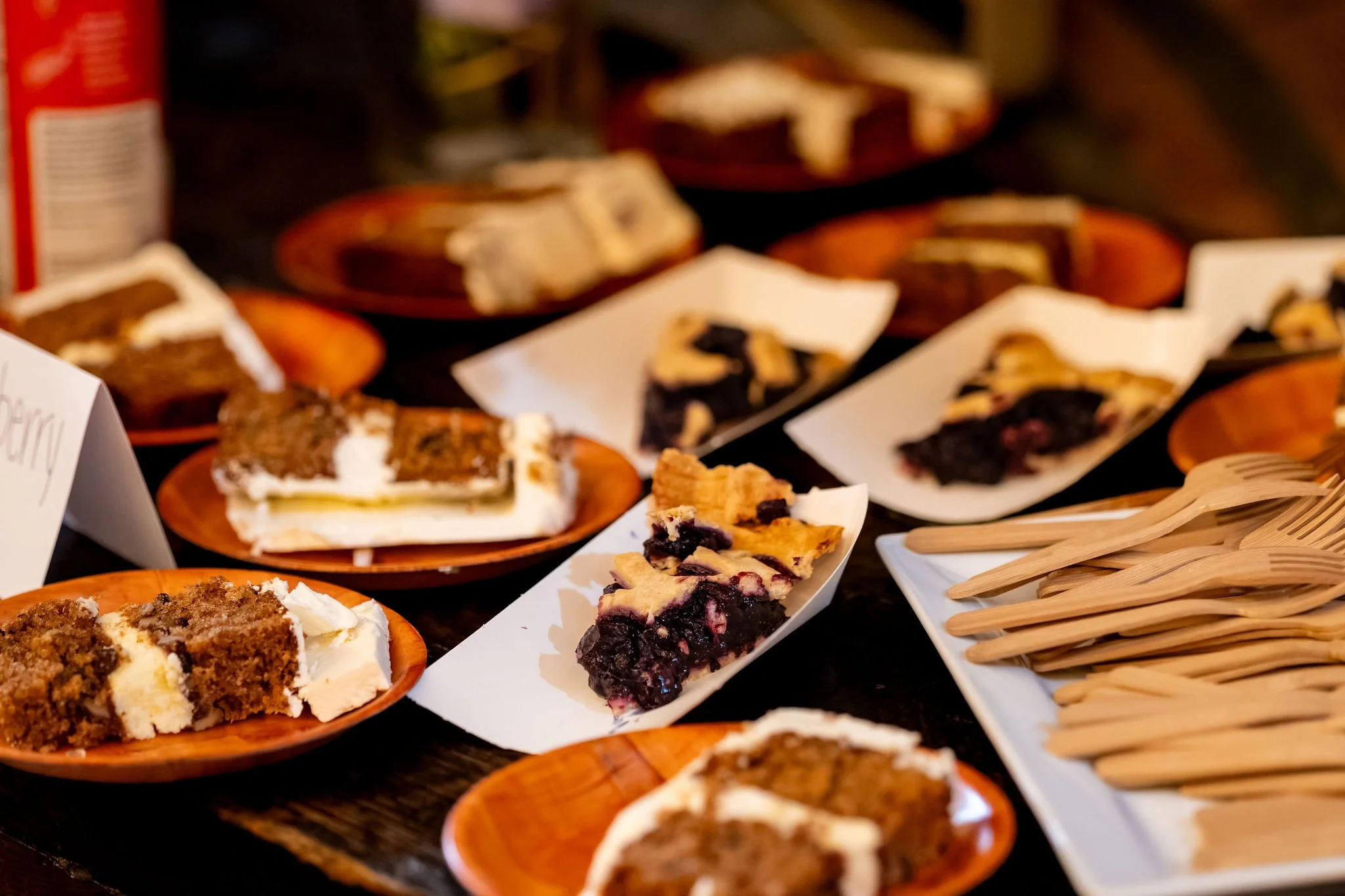 Slices of wedding cake and blueberry pie set out on wooden plates for guests at The Cellars at Allagash Brewing Company in Portland Maine fall wedding photography VMG Productions