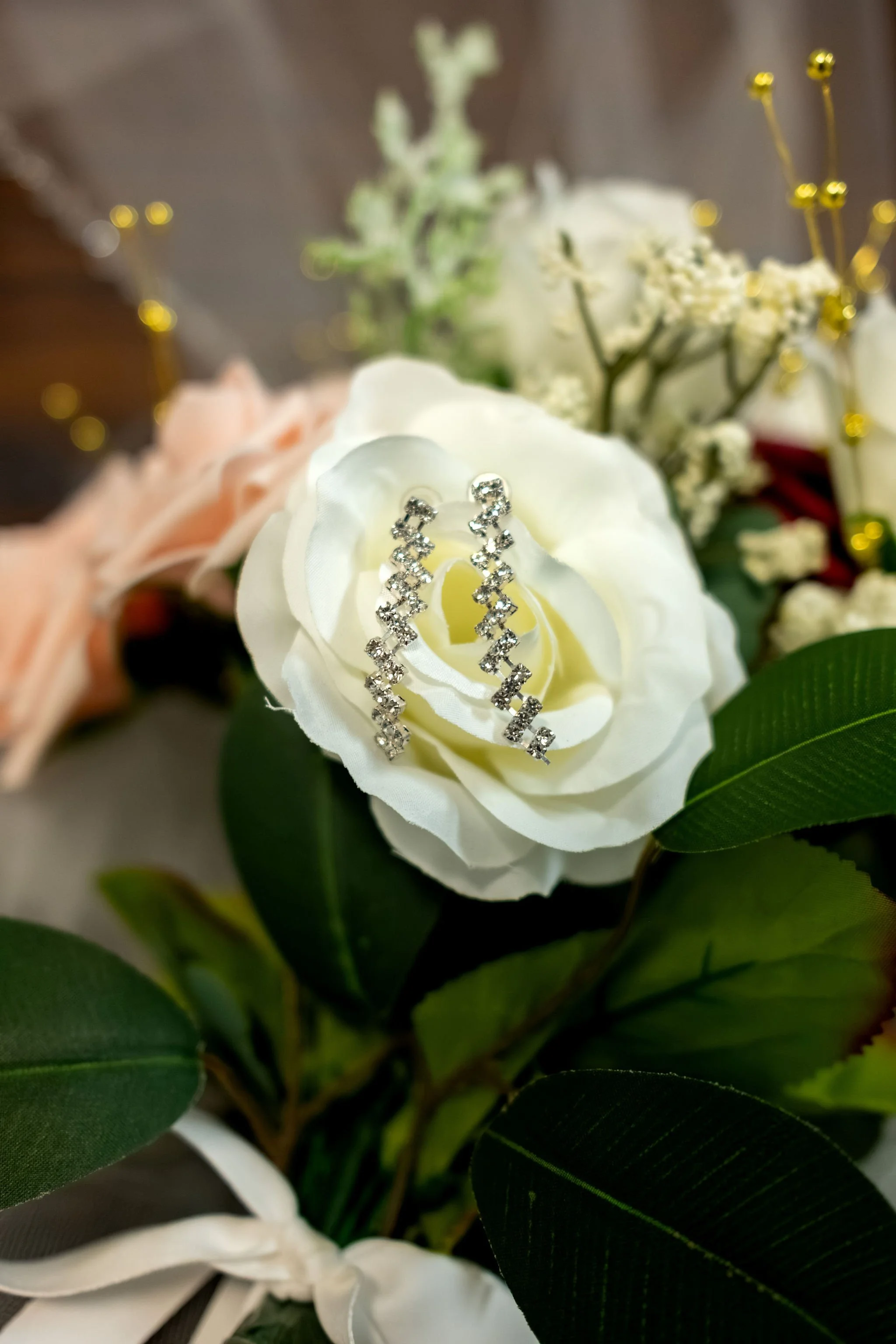 Jeremiah and Vienna drop earrings styled among bouquet florals with shallow depth of field at Holy Trinity Greek Orthodox Church Portland Maine spring wedding photography VMG Productions