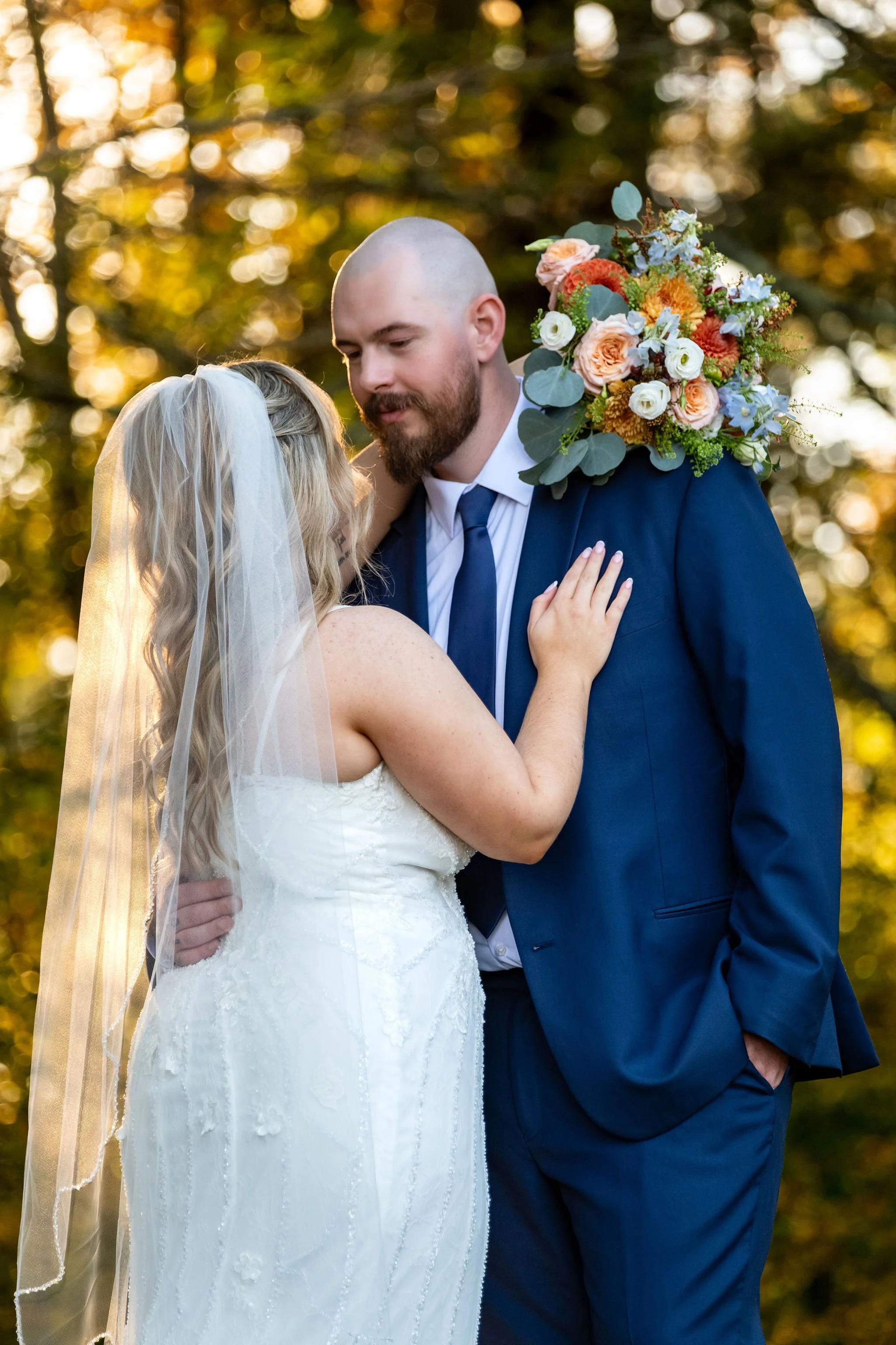 Close portrait of Sam and Ellie holding each other with her veil falling down her back at Boothbay Playhouse in Boothbay Maine fall wedding photography VMG Productions