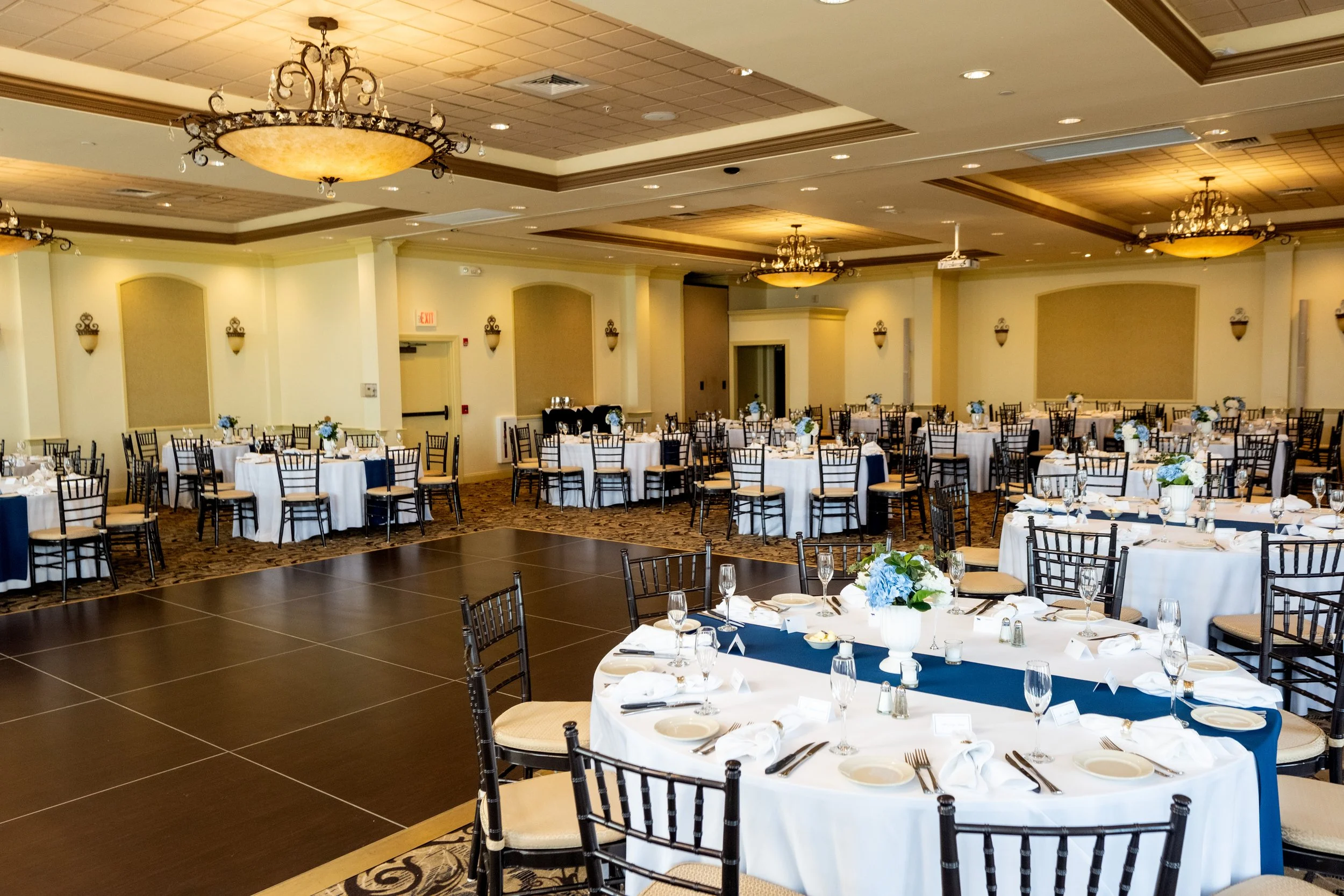 The ballroom at Union Bluff Hotel set for the reception with navy runners hydrangea centerpieces and the open dance floor in York Maine wedding photography VMG Productions