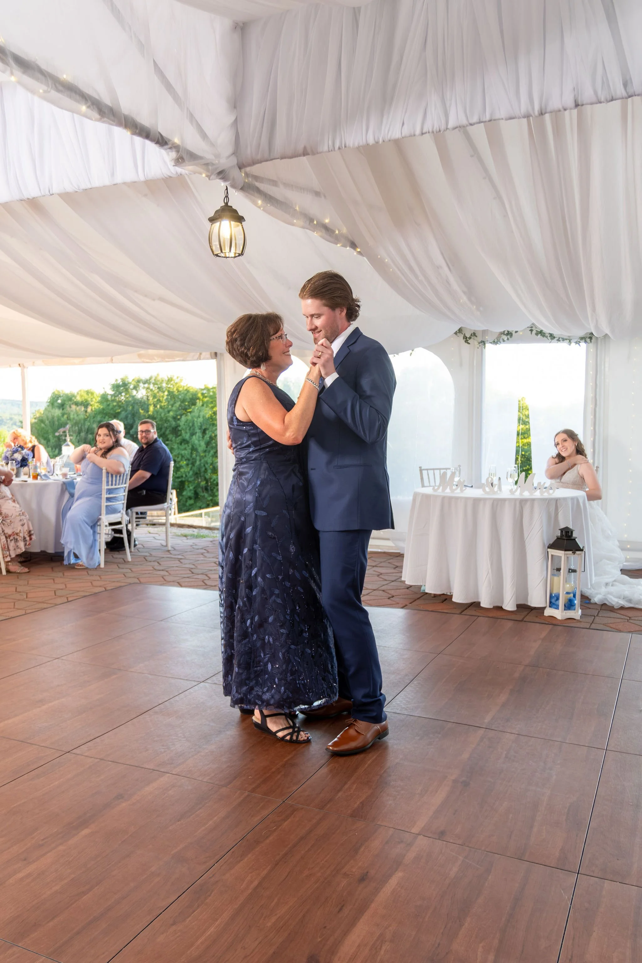 Zachary dancing with his mom in navy on the tent dance floor at The Lucerne Inn in Dedham Maine summer wedding photography VMG Productions