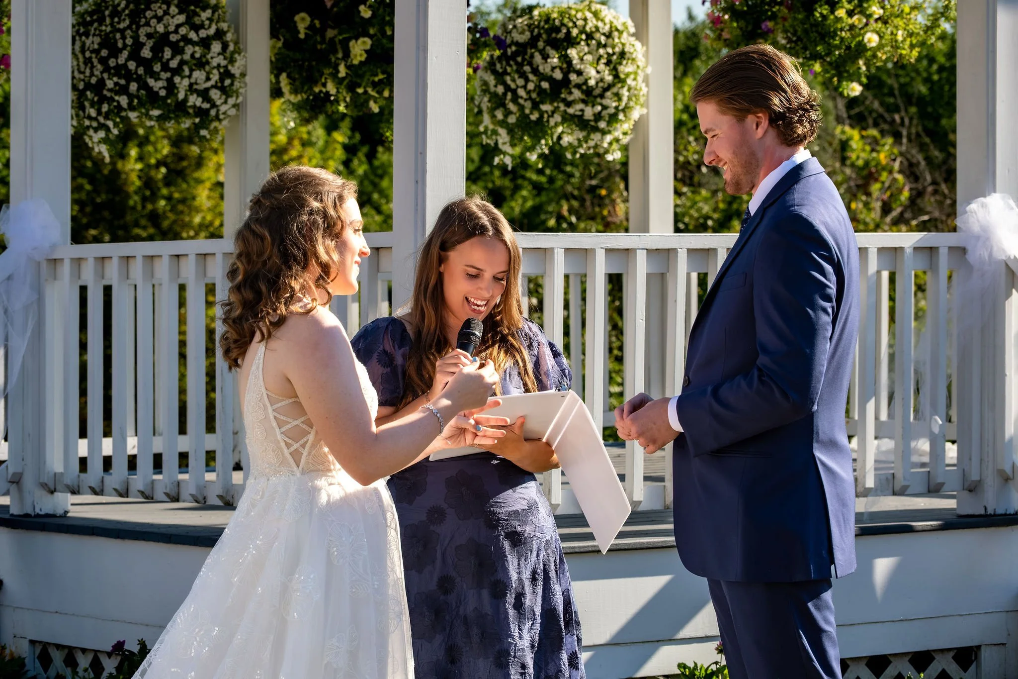 Zachary and Hollie exchanging vows in front of the officiant on the white gazebo at The Lucerne Inn in Dedham Maine summer wedding photography VMG Productions