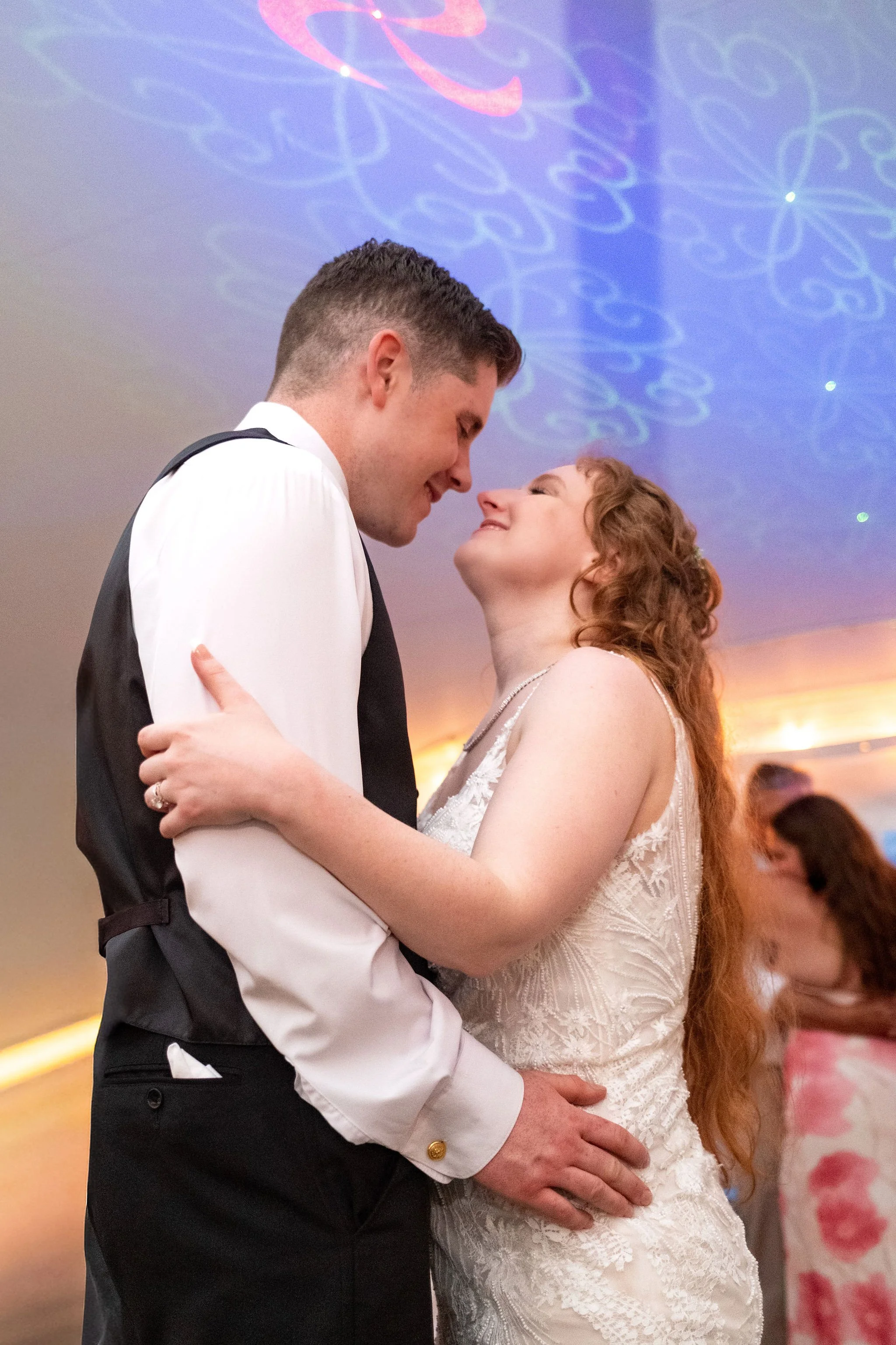 Kayla and Ethan DeAngelis nose to nose under the purple dance floor lights inside the reception tent at their Sanbornton New Hampshire wedding photography VMG Productions