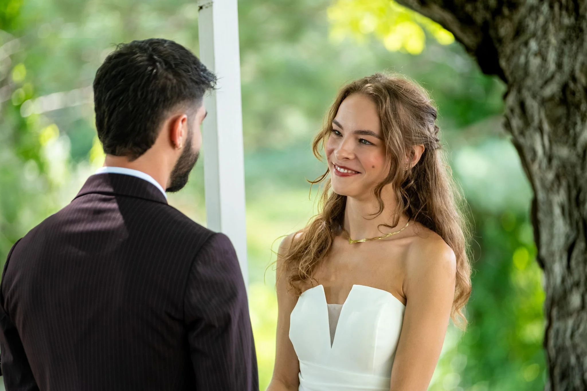 Cassidy Begin smiling at Chase across the arbor during their ceremony at Maple Hill Farm Inn and Conference Center in Hallowell Maine summer wedding photography VMG Productions