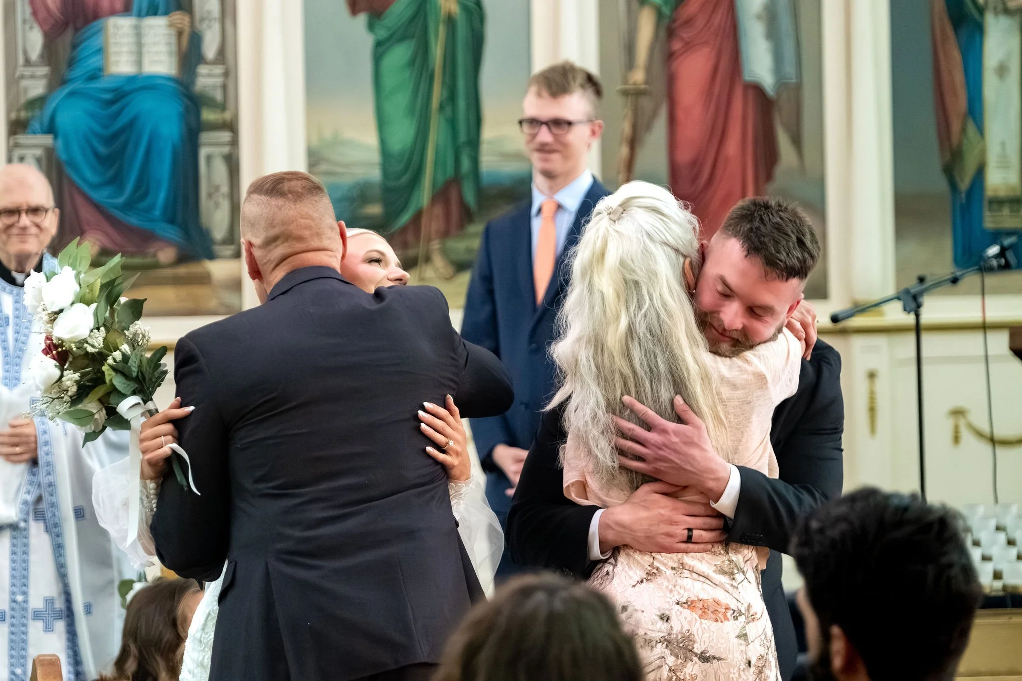 Jeremiah and Vienna share heartfelt embraces with family members after the ceremony at Holy Trinity Greek Orthodox Church Portland Maine spring wedding photography VMG Productions