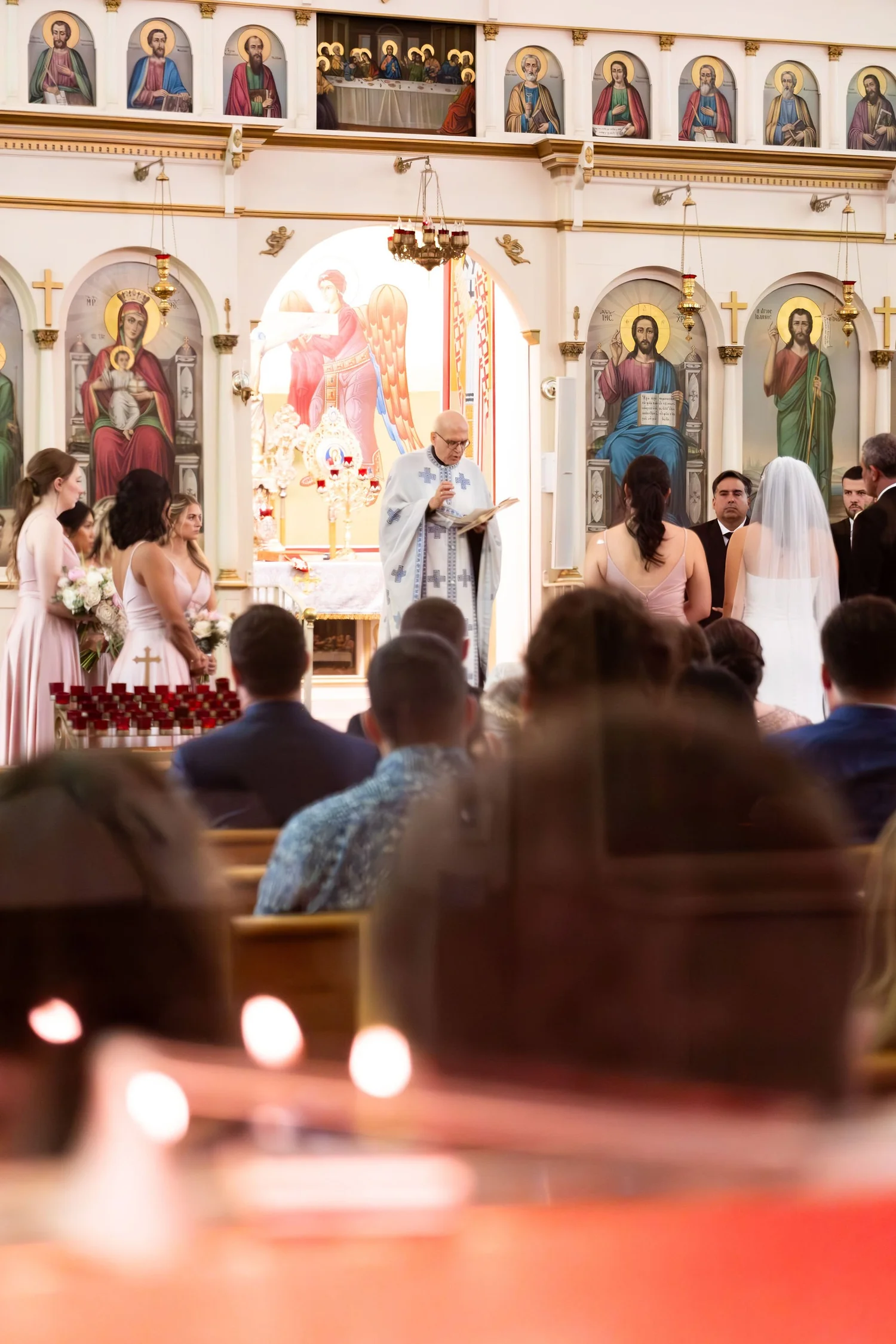 Nicole and Alexey's ceremony seen from the pews beneath the icons at Holy Trinity Greek Orthodox Church Portland Maine summer wedding photography VMG Productions