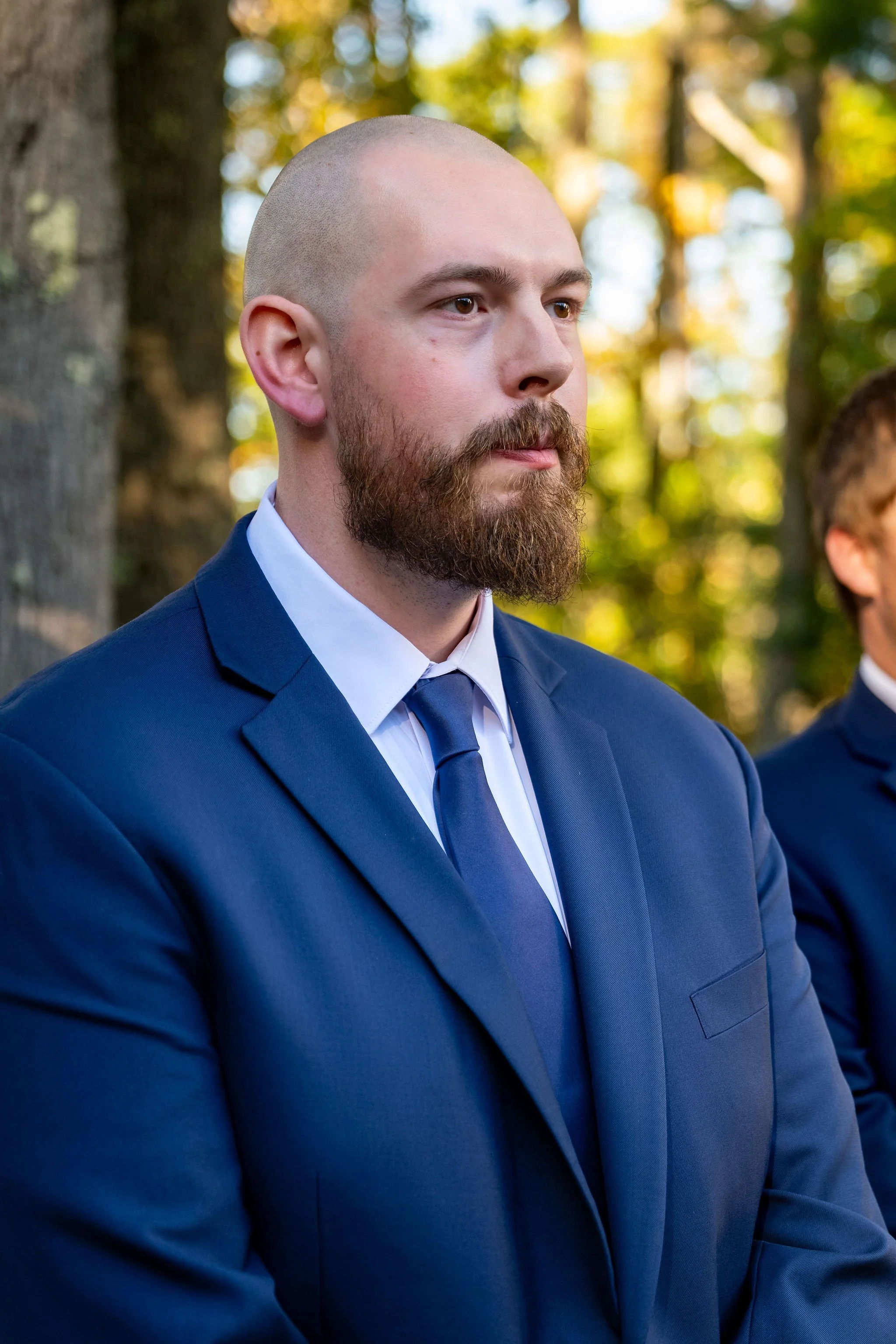 Sam waiting at the front of the aisle with a serious, emotional expression in his navy suit at Boothbay Playhouse in Boothbay Maine fall wedding photography VMG Productions