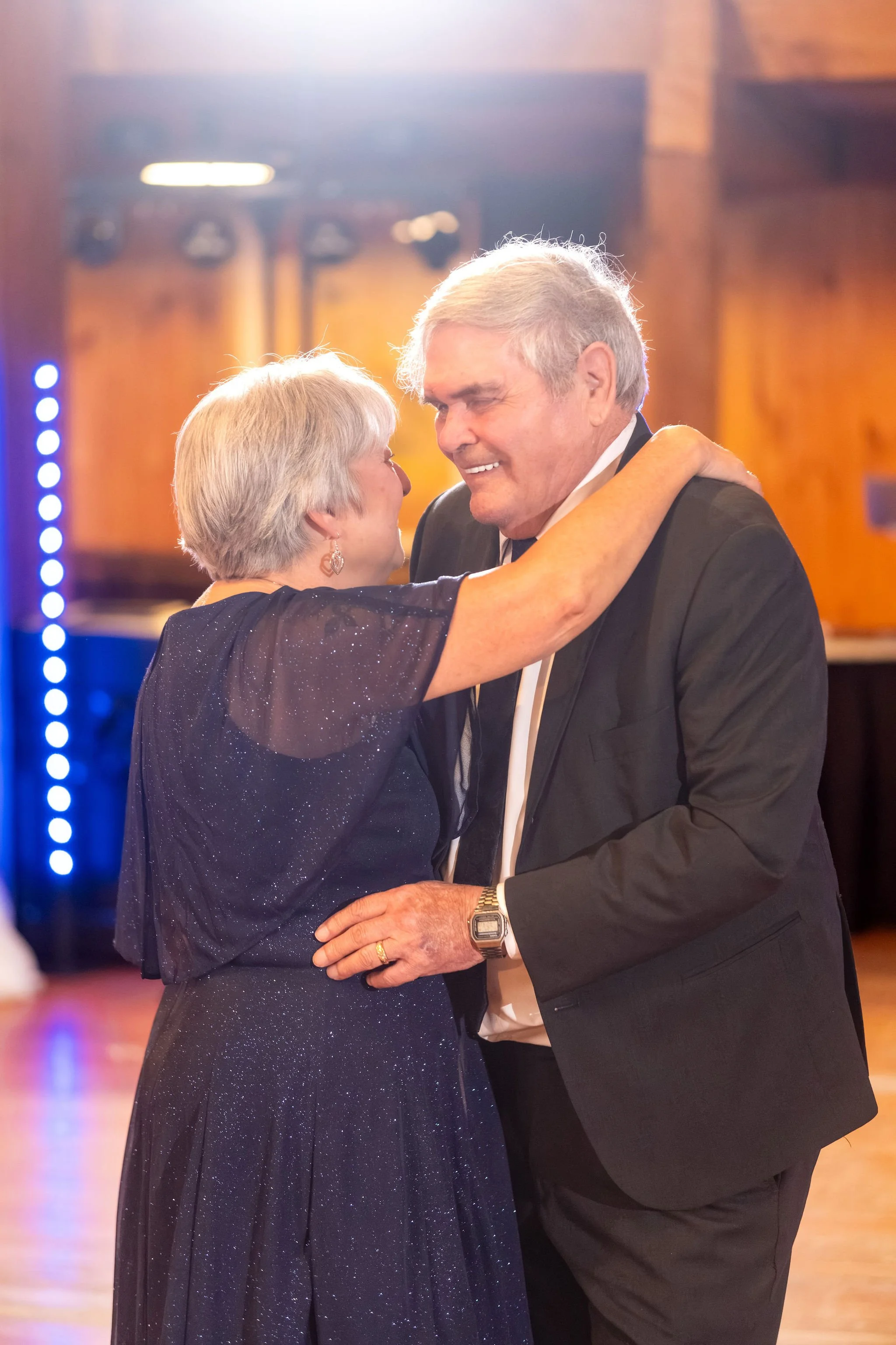 An older couple smiling as they slow dance together on the barn floor at Boothbay Playhouse in Boothbay Maine fall wedding photography VMG Productions