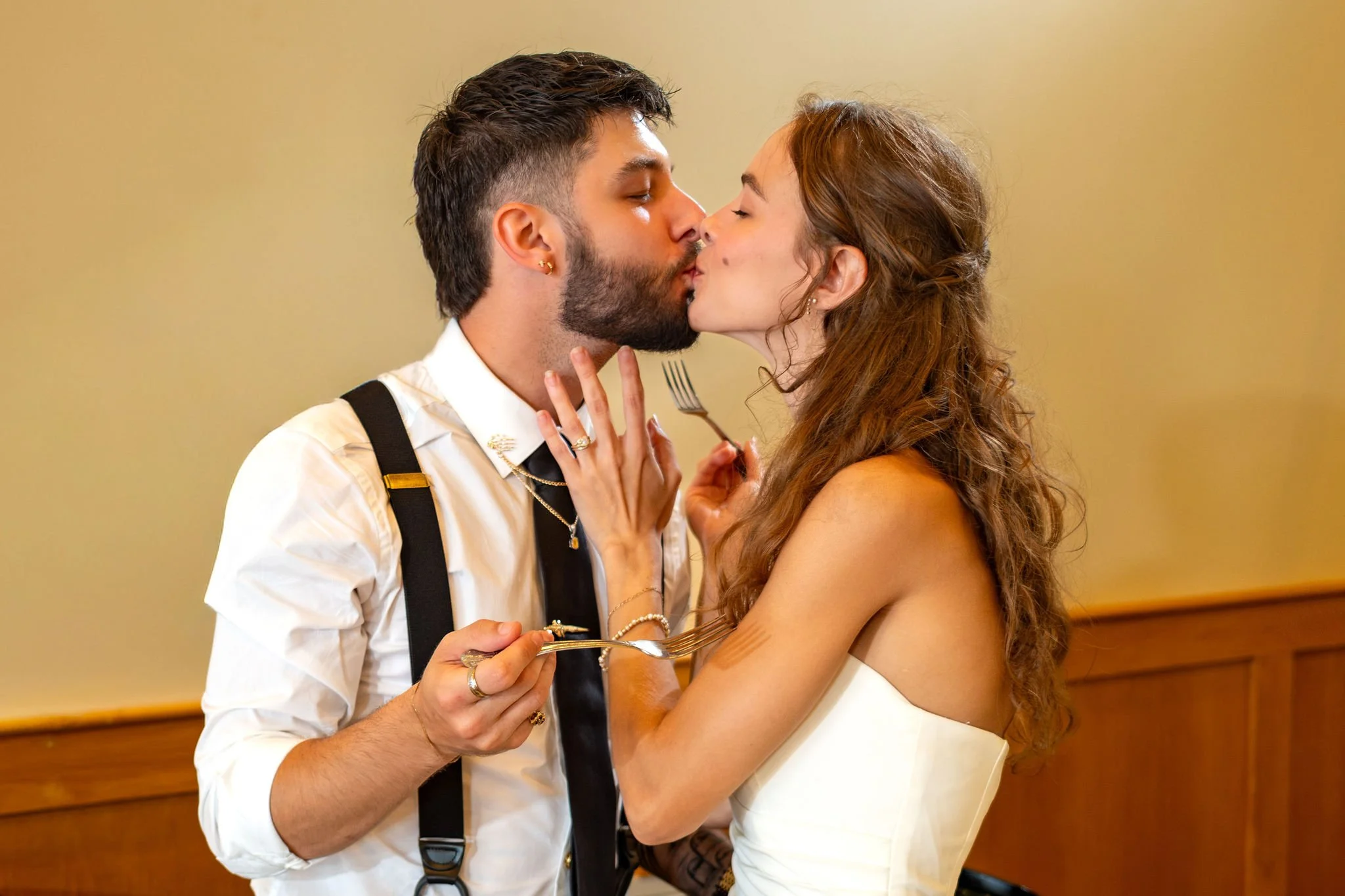 Cassidy and Chase Begin kissing with forks in hand after cutting the cake at Maple Hill Farm Inn and Conference Center in Hallowell Maine summer wedding photography VMG Productions