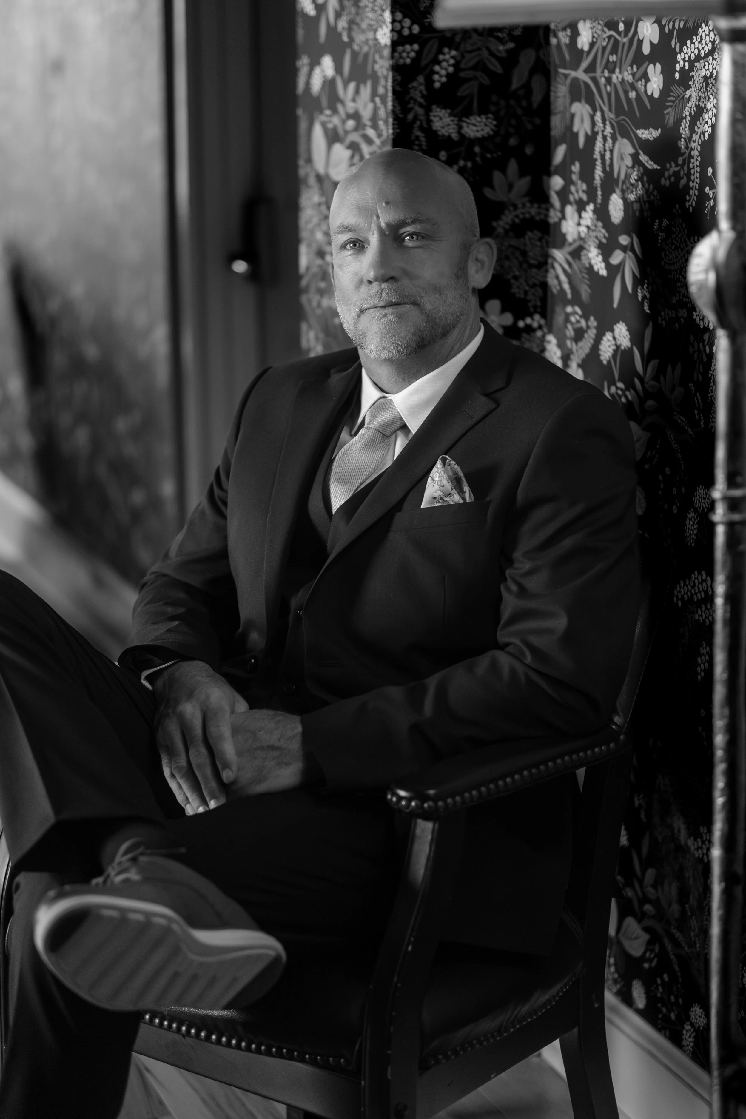 Marc Draper seated portrait against the floral wallpaper before the ceremony in black and white at The Breakwater Inn in Kennebunkport Maine summer wedding photography VMG Productions