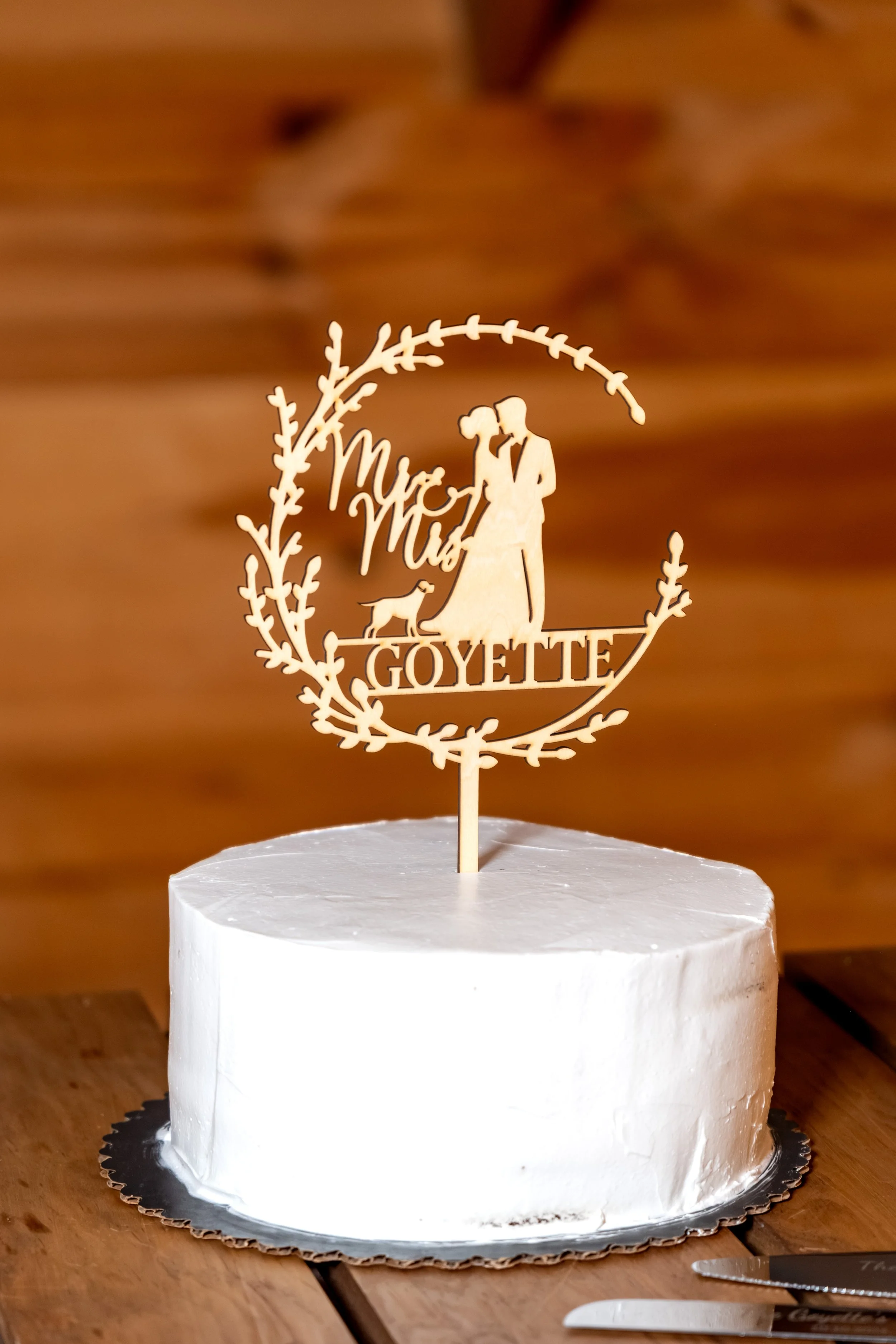 Close detail of the white cake with a wooden topper showing the couple and their dog at the Maine Wedding Barn and Event Center in Minot Maine fall wedding photography VMG Productions