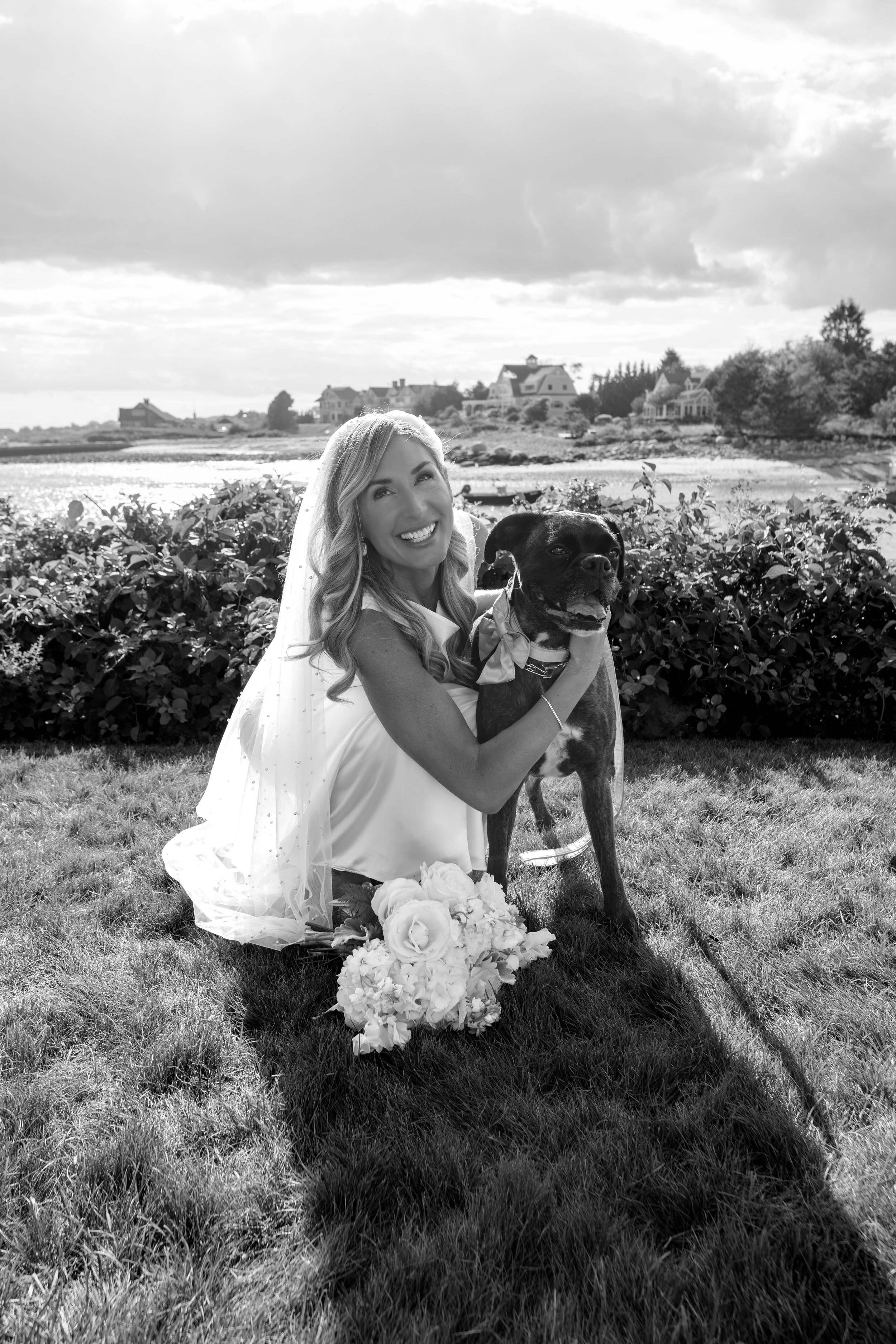 Ashley Draper kneeling with Lula in her bow after the ceremony in black and white at The Breakwater Inn in Kennebunkport Maine summer wedding photography VMG Productions